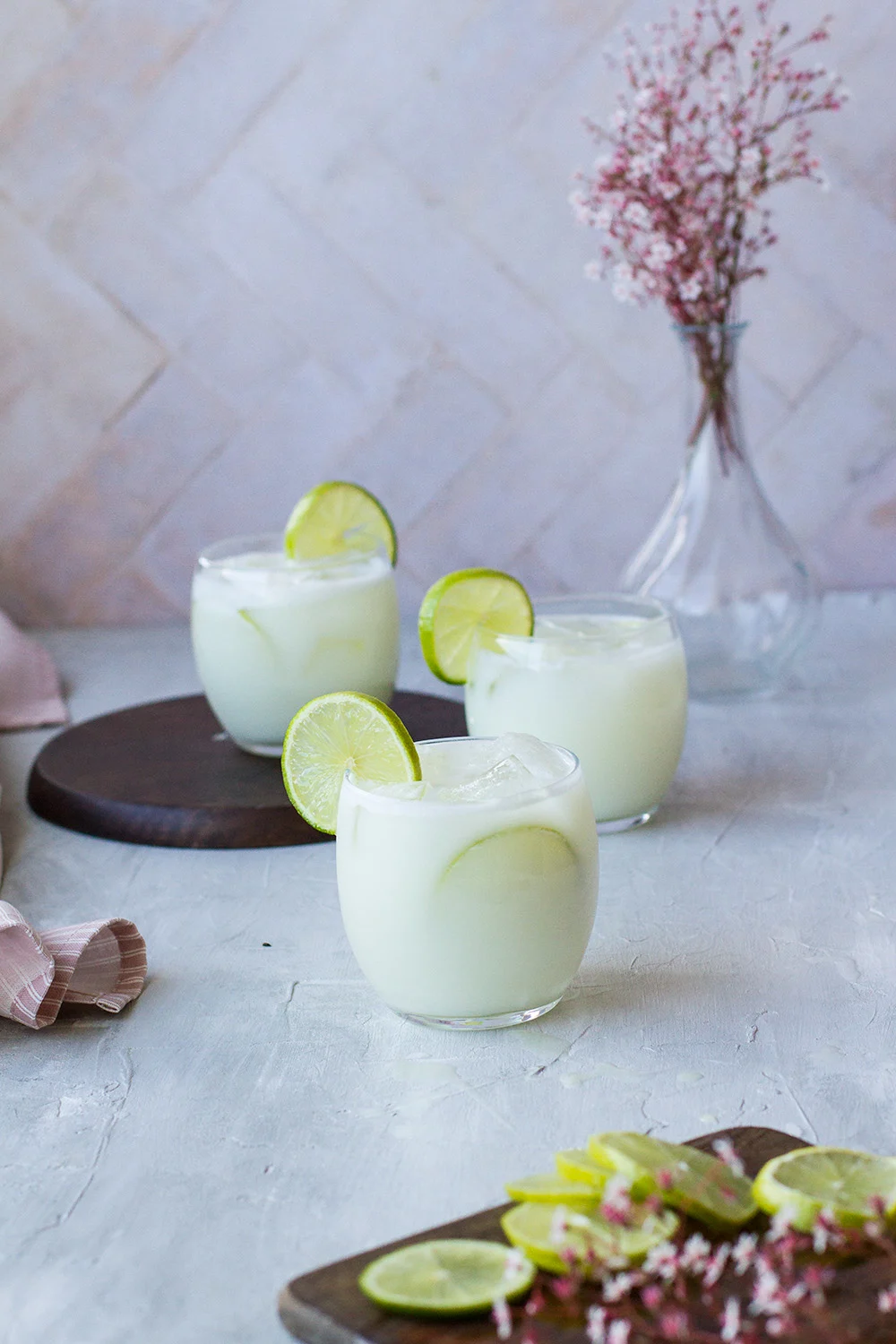 Round glasses filled with Swiss lemonade and garnished with lime wheels.