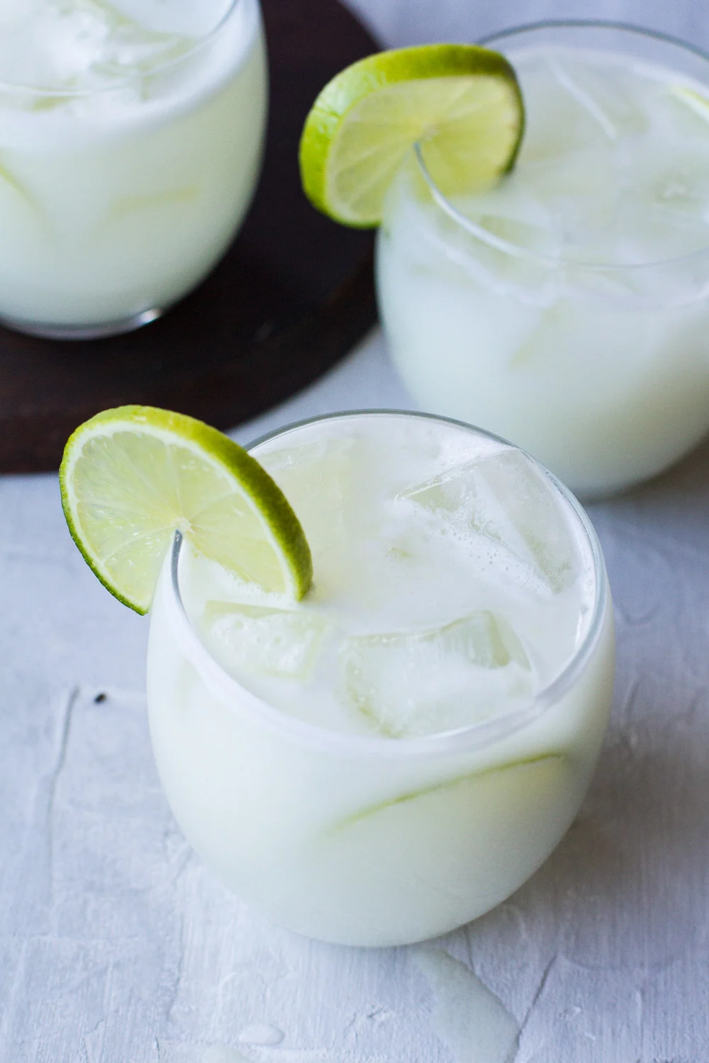 Close-up of a glass filled with ice and Brazilian lemonade, garnished with lime.