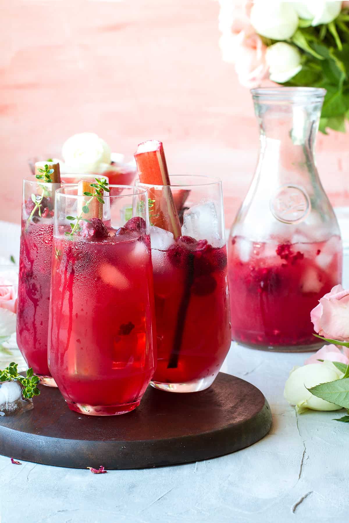 Three glasses with pink iced tea in the front and a decanted in the background.