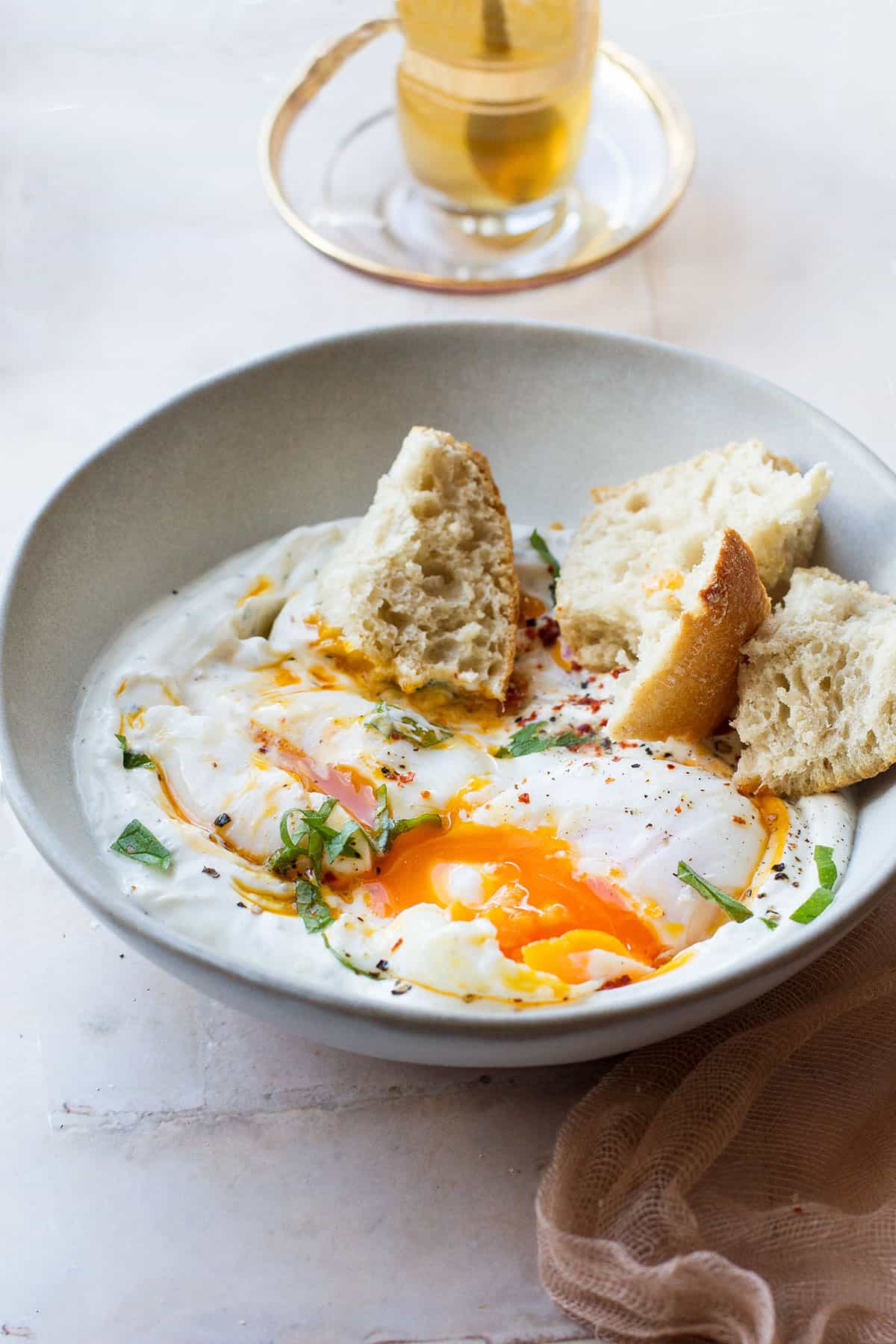 Bowl of garlic yogurt, poached eggs and crusty bread.