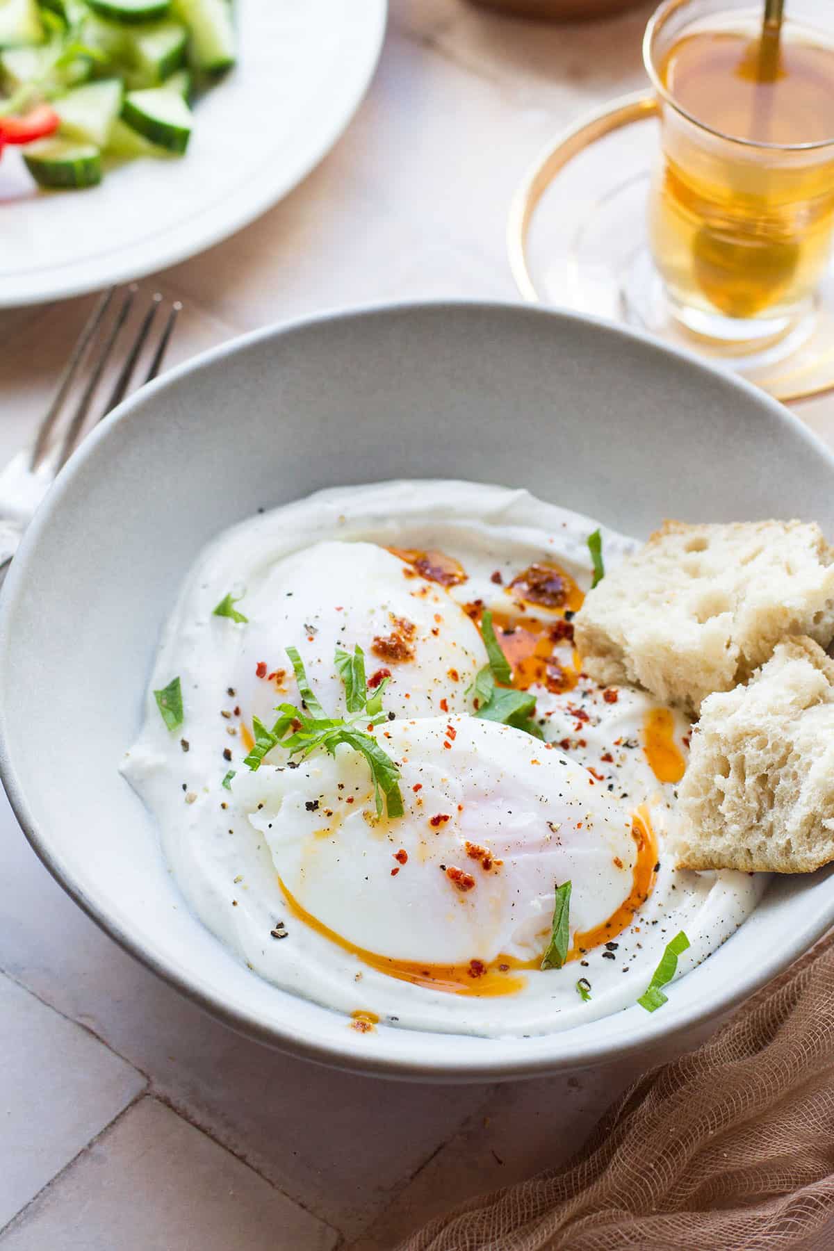 Two eggs on a bed of garlic yogurt in a large bowl.