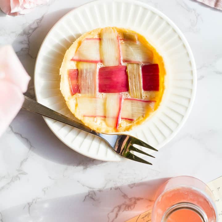 Tart with strips of rhubarb like a lattice pattern, bottle with rhubarb syrup on the side.