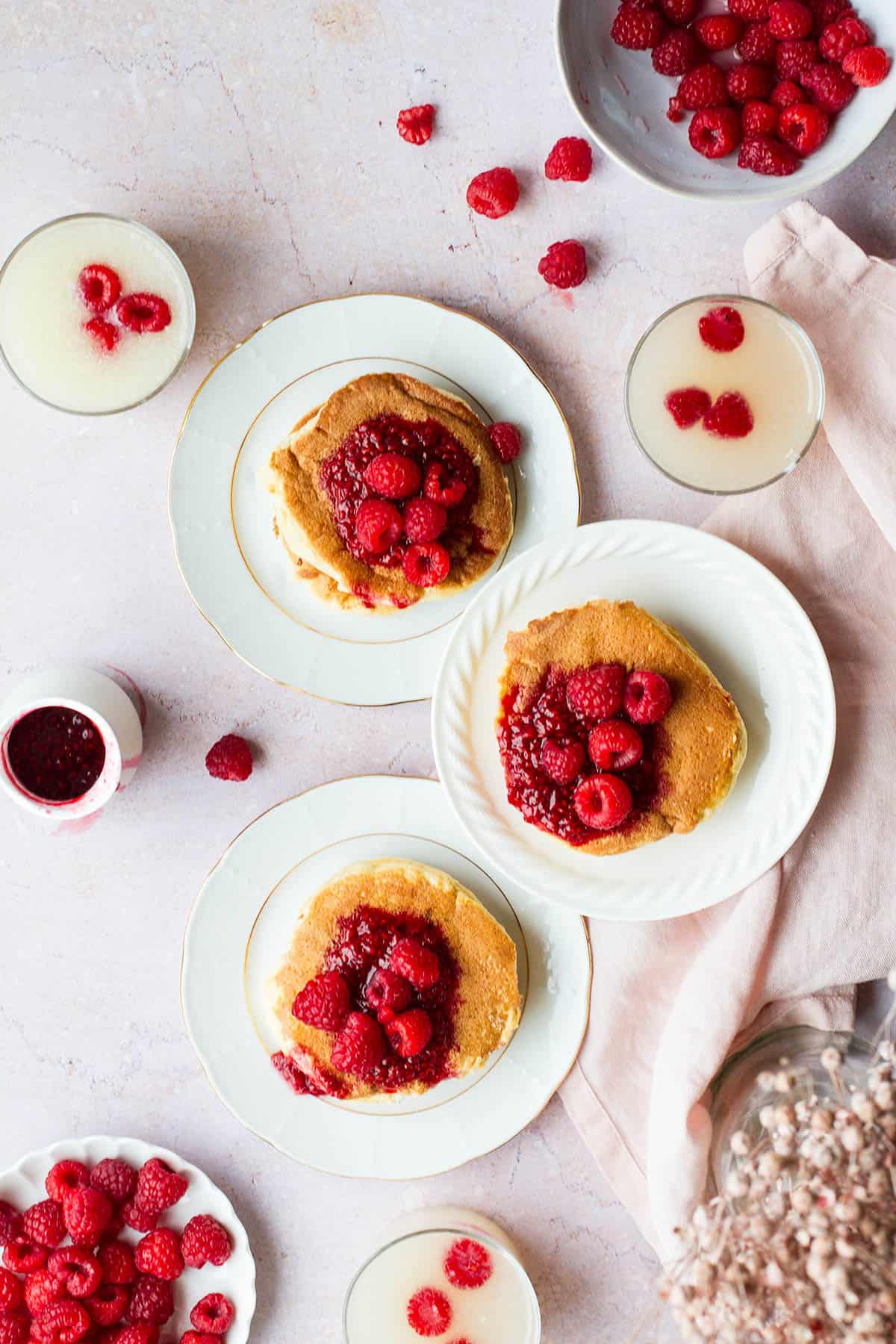 Three plates with Japanese pancakes and raspberry sauce seen from above.
