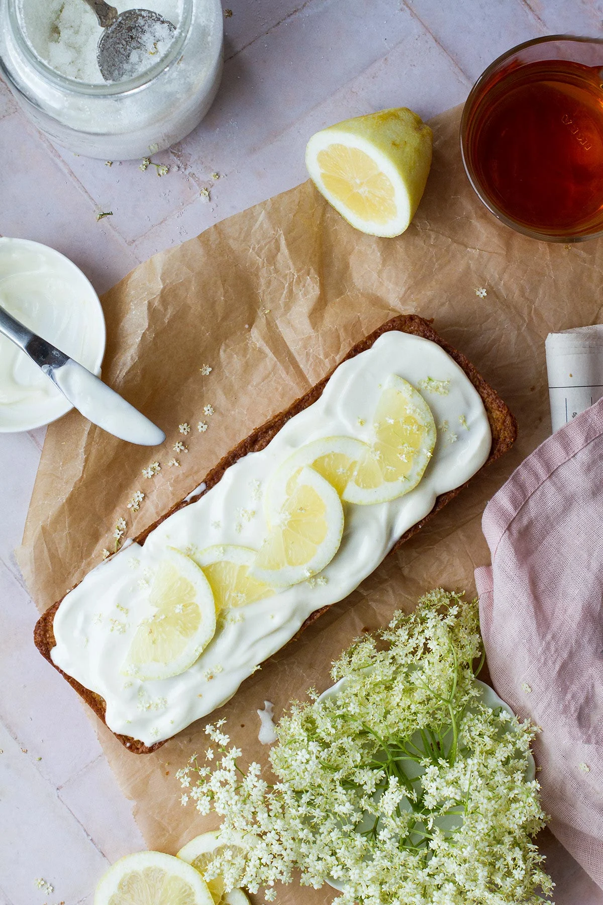 Lemon zucchini bread garnished with slices of lemon and fresh elderflowers.