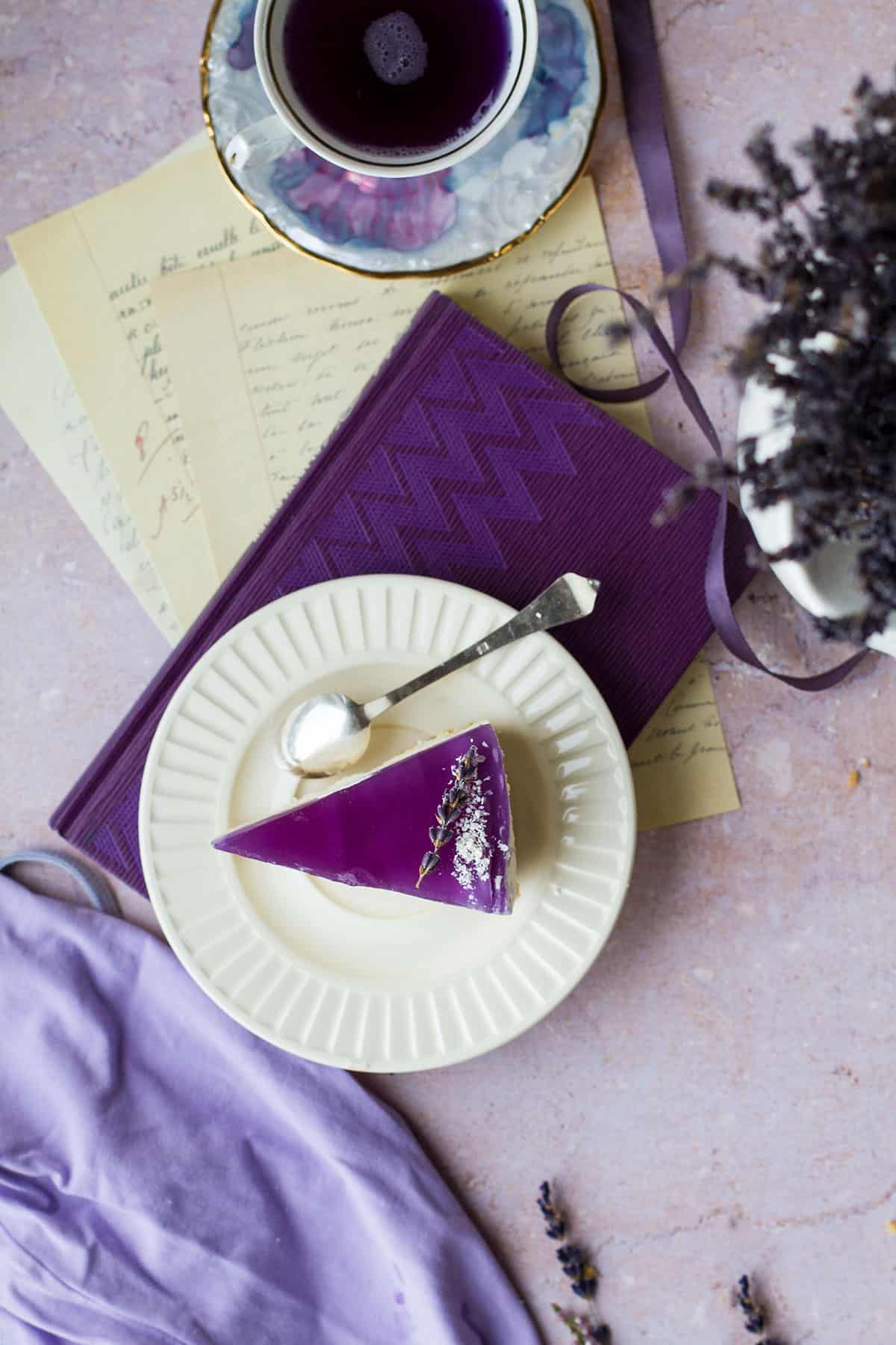 A slice of cheesecake with a puprple jelly lid on a vintage plate, purple background.