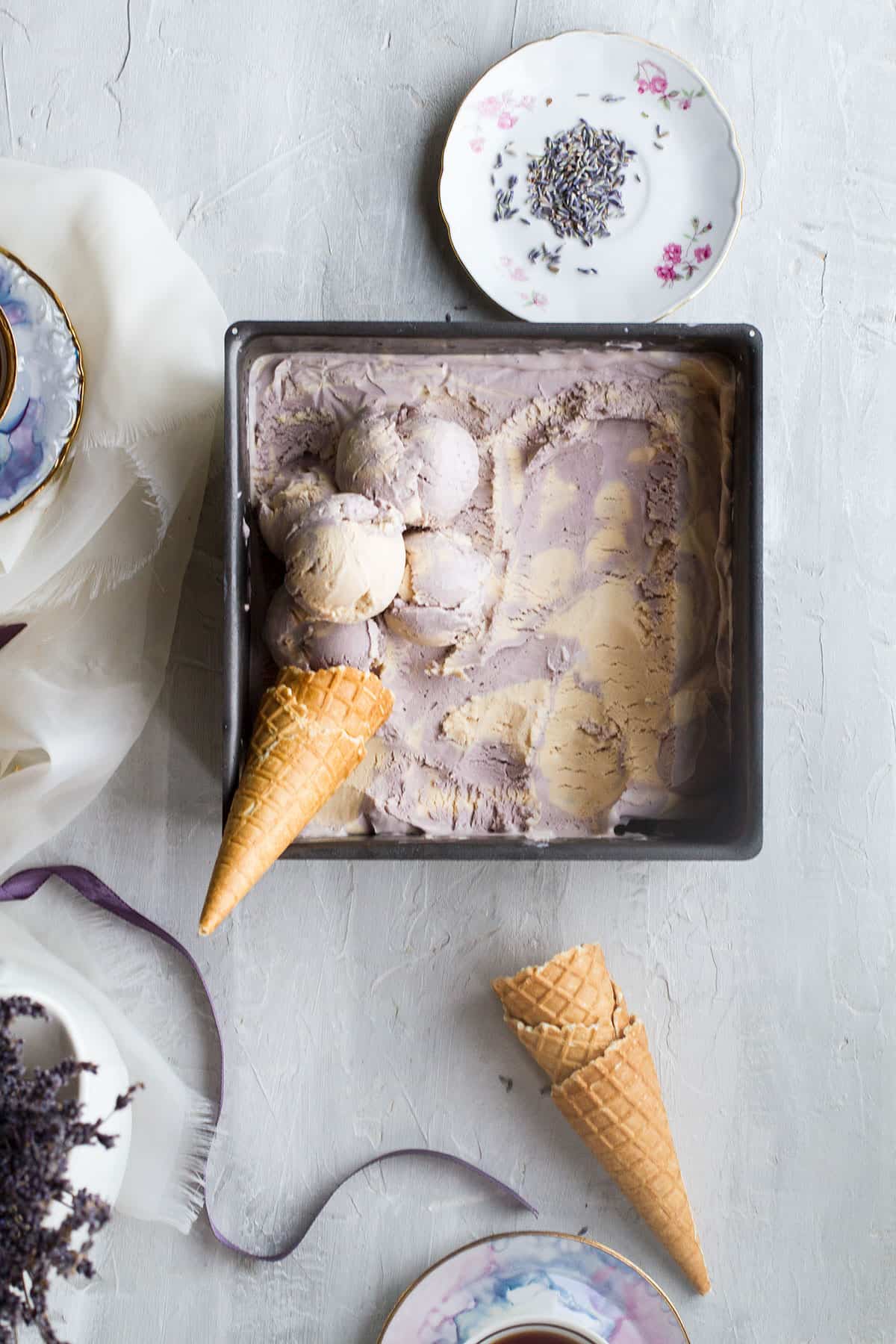 A square baking pan with purple and beige swirls of ice cream and a waffle cone.