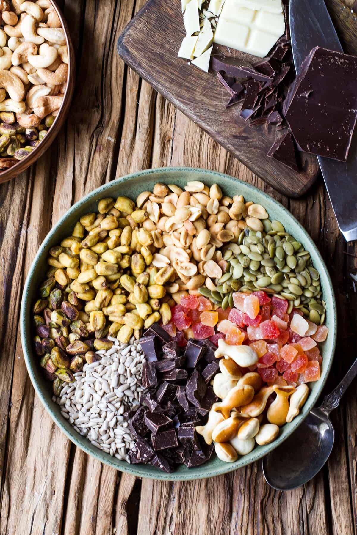 A green bowl with hiking trail mix, divided.