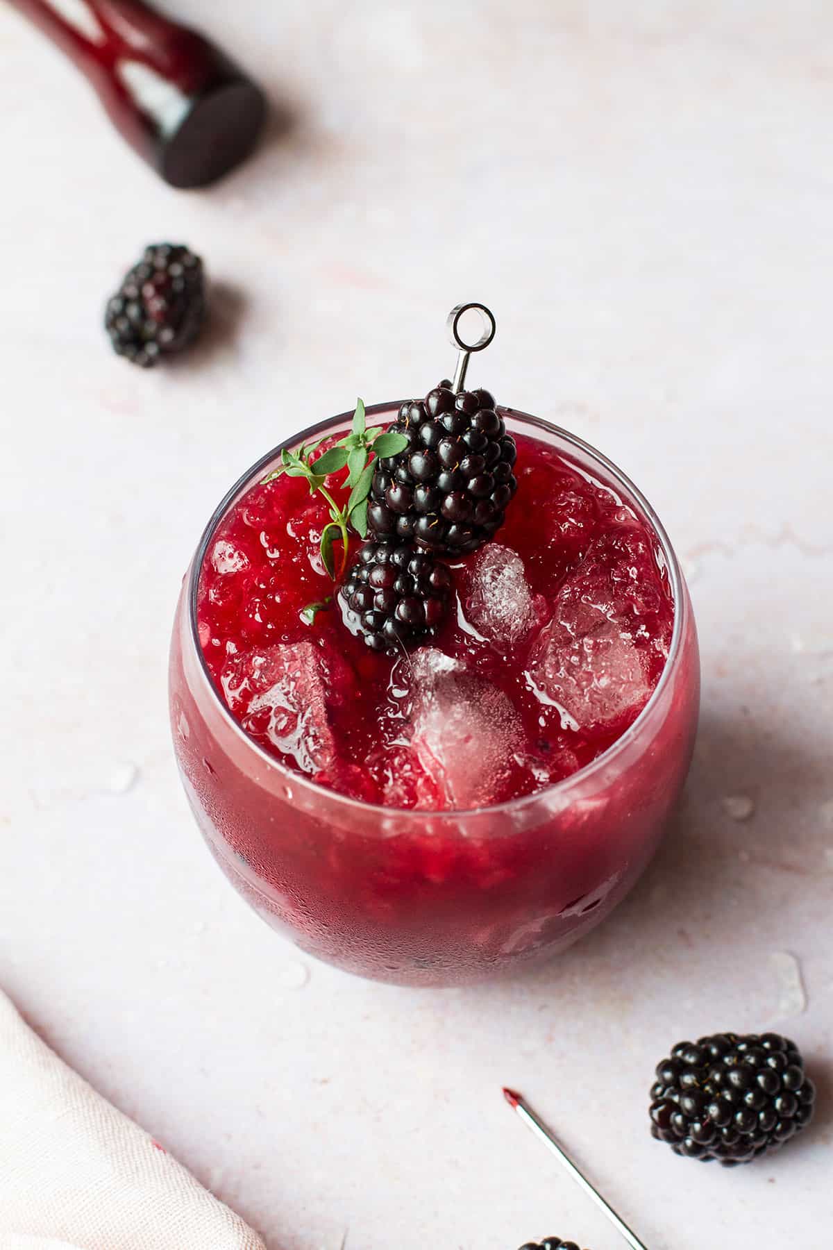Round glass with blackberry whiskey smash and blackberry garnish.