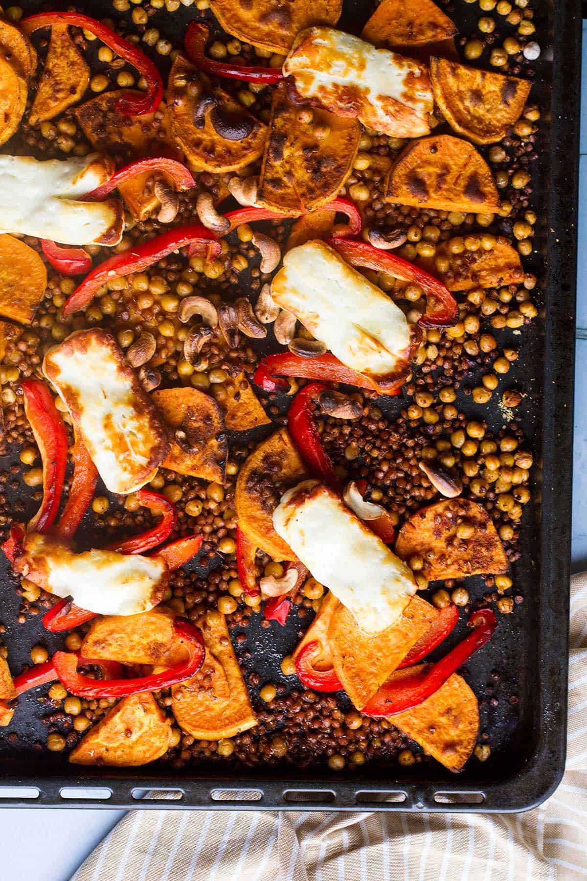 Close-up of sheet pan with sweet potato slices and halloumi.