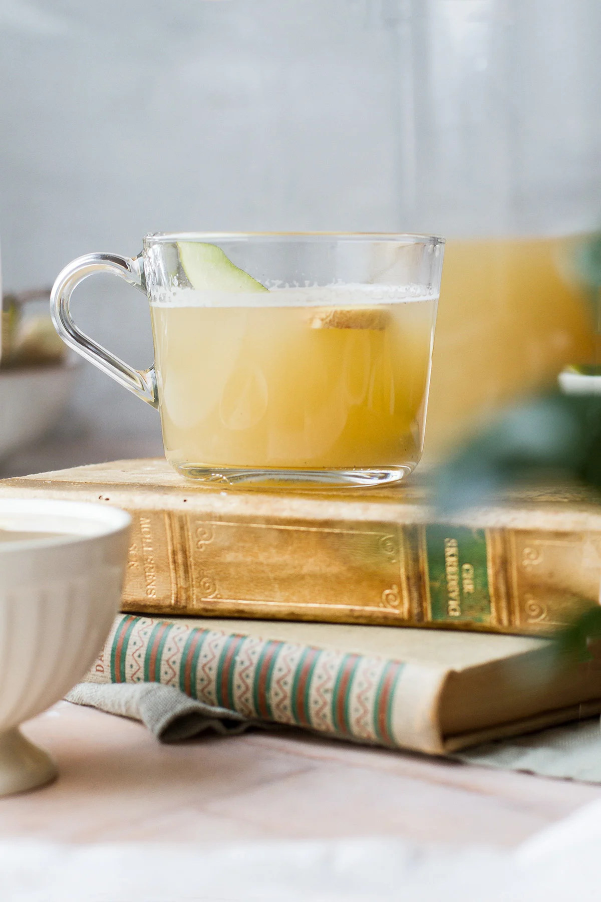 A glass cup with mulled white wine on top of two old books.