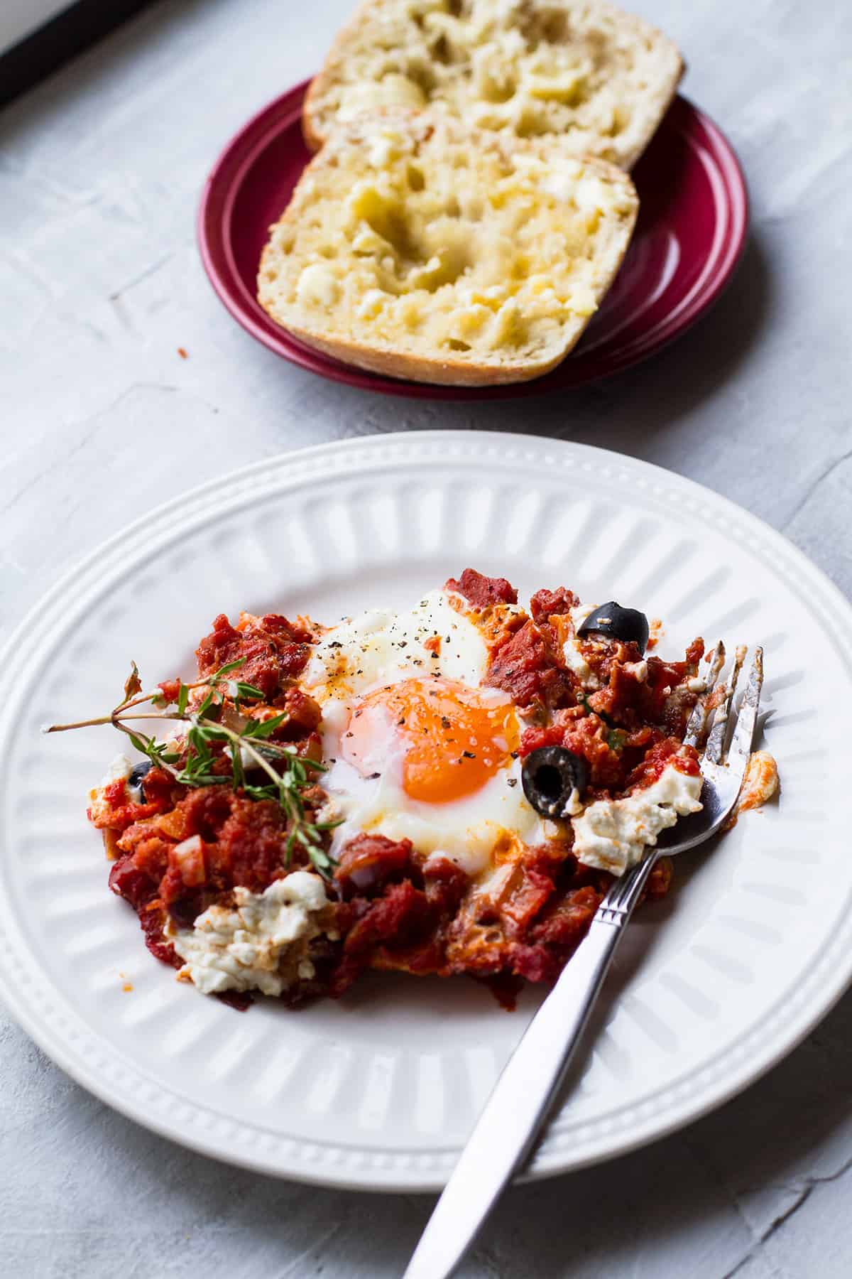 White plate with shakshuka and one egg.