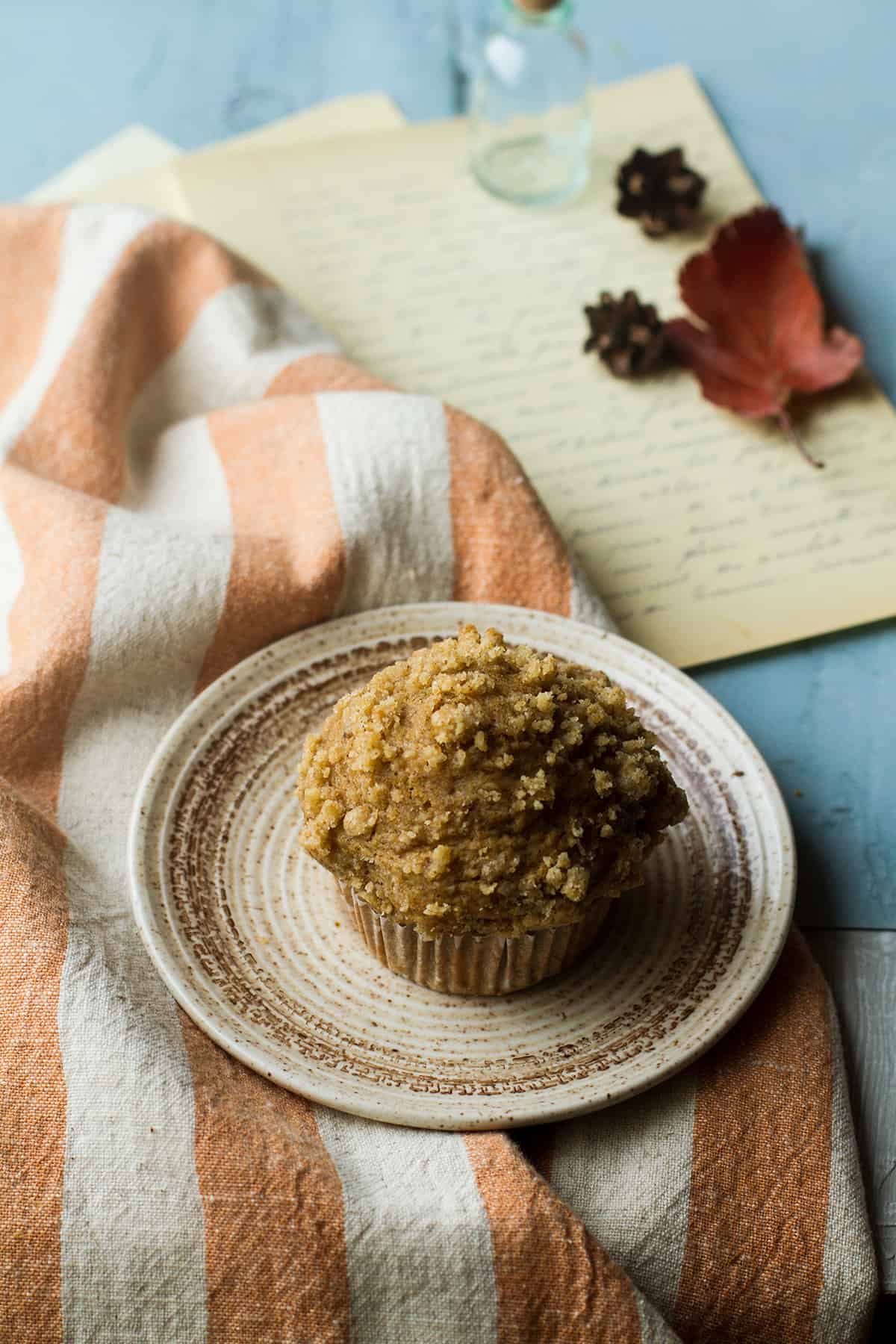 One muffin with crumb topping on a small plate.