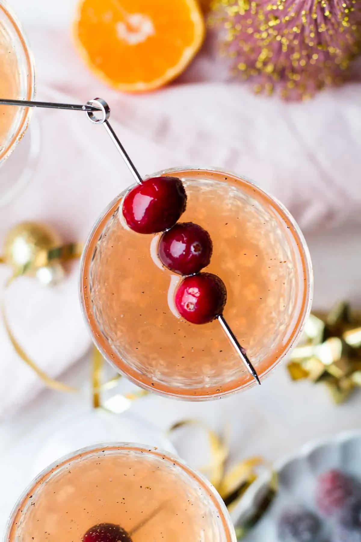One cocktail seen from above with three cranberries on a cocktail pin.