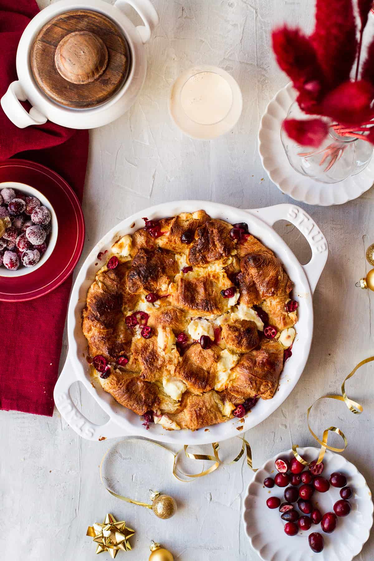 A white pie pan with croissant French toast casserole. Red decorations around.