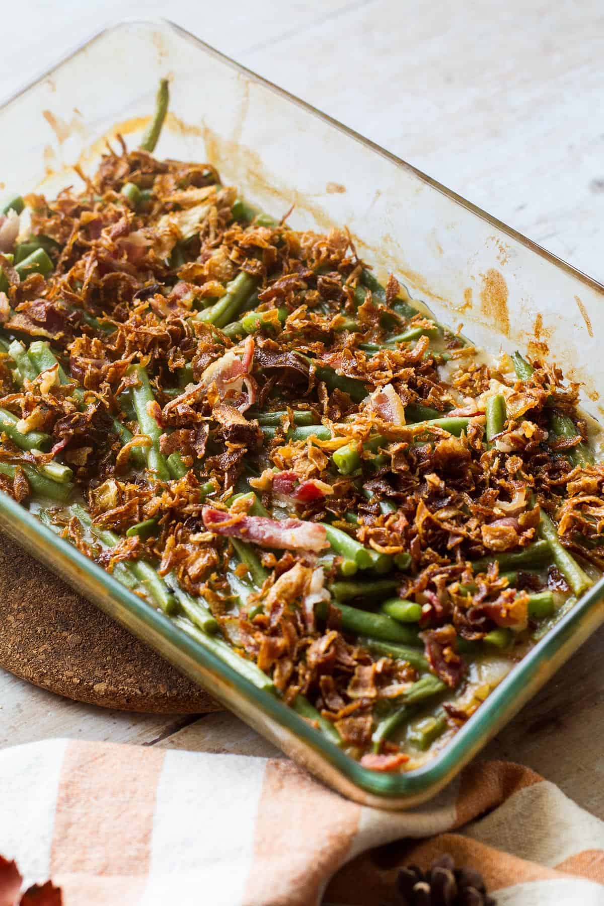 Green bean casserole with crispy onion on top in a glass dish.