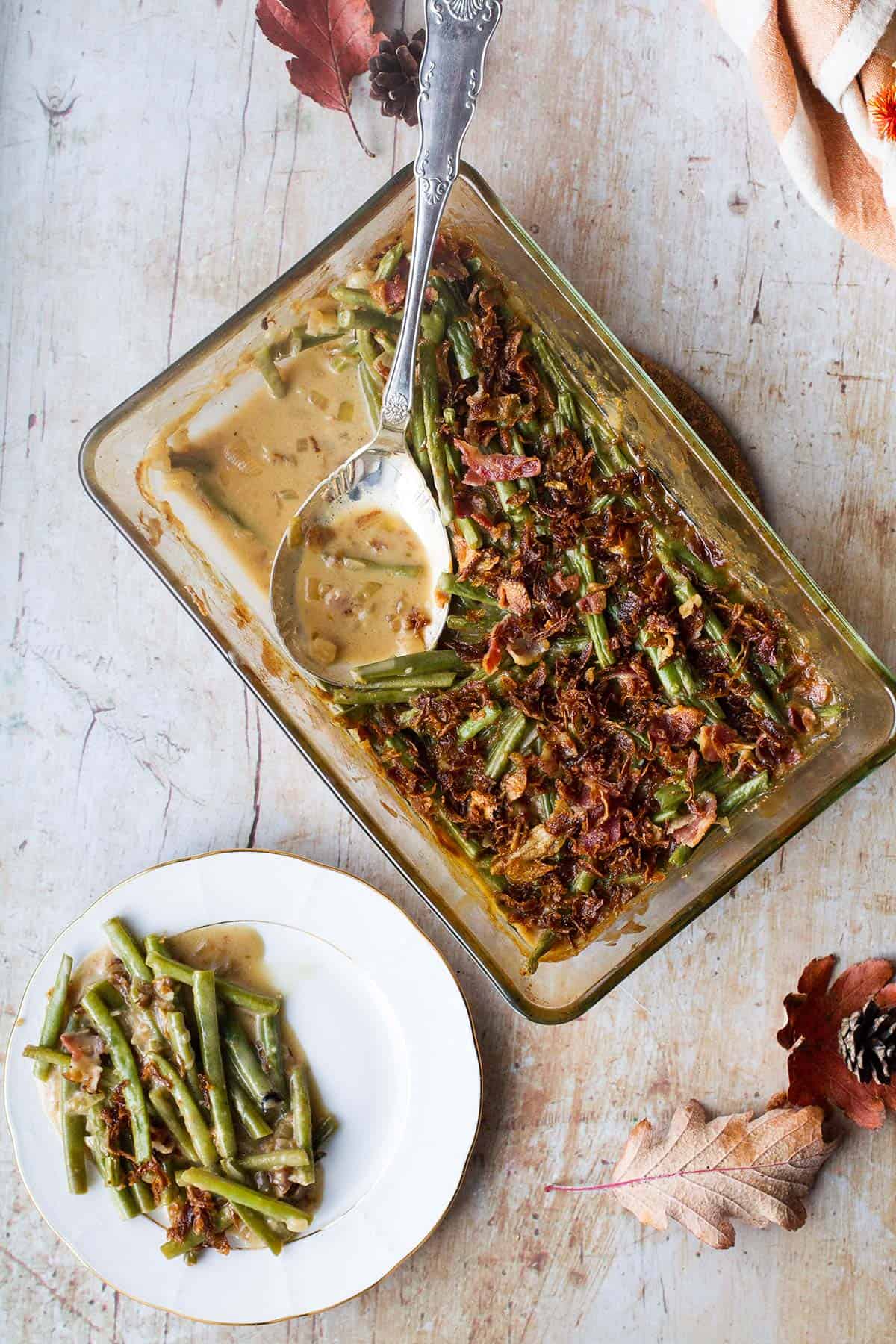 A large vintage spoon in the green bean casserole dish and one white plate for serving.
