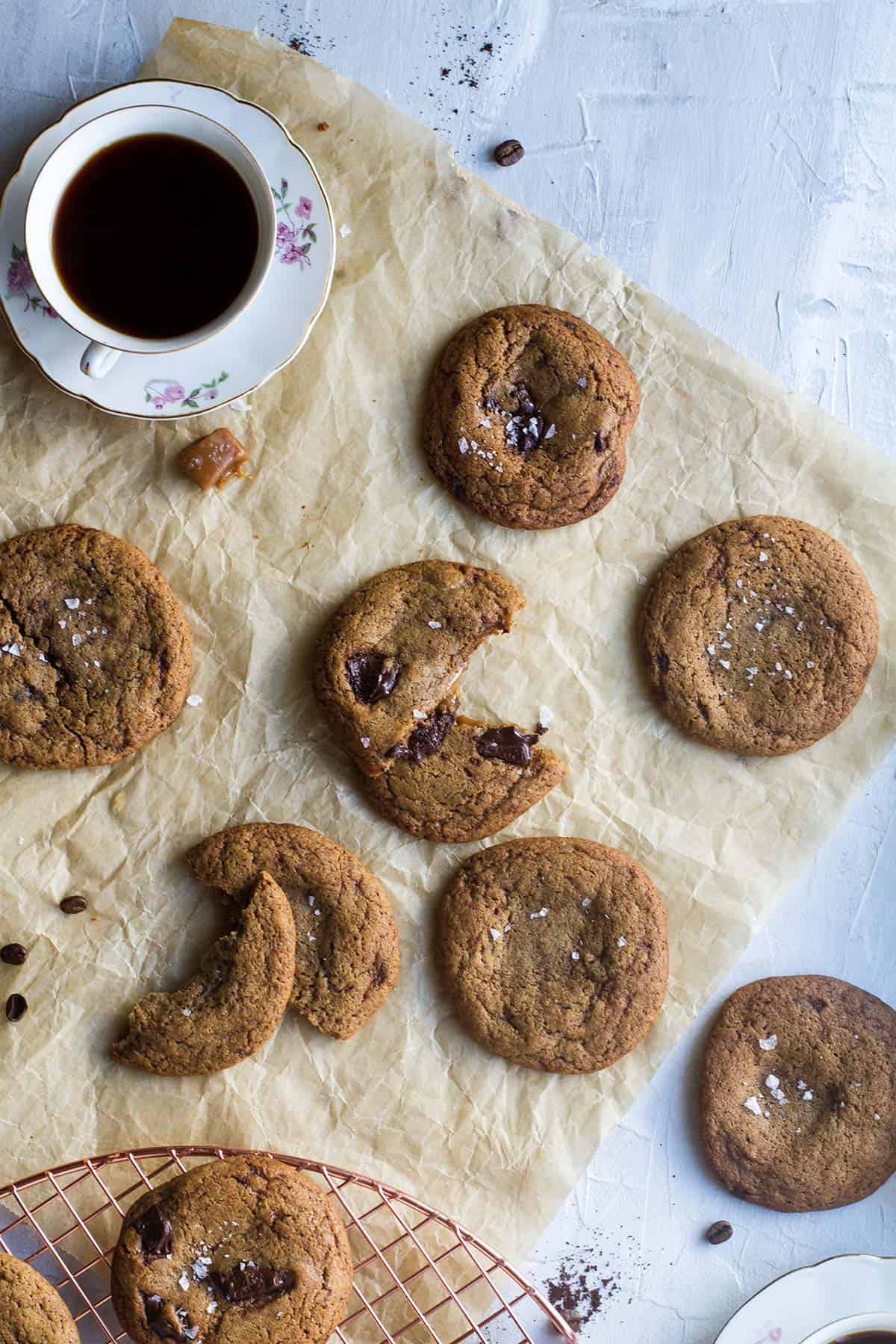 Coffee cookies on a parchment paper, some broken to show the caramel inside.