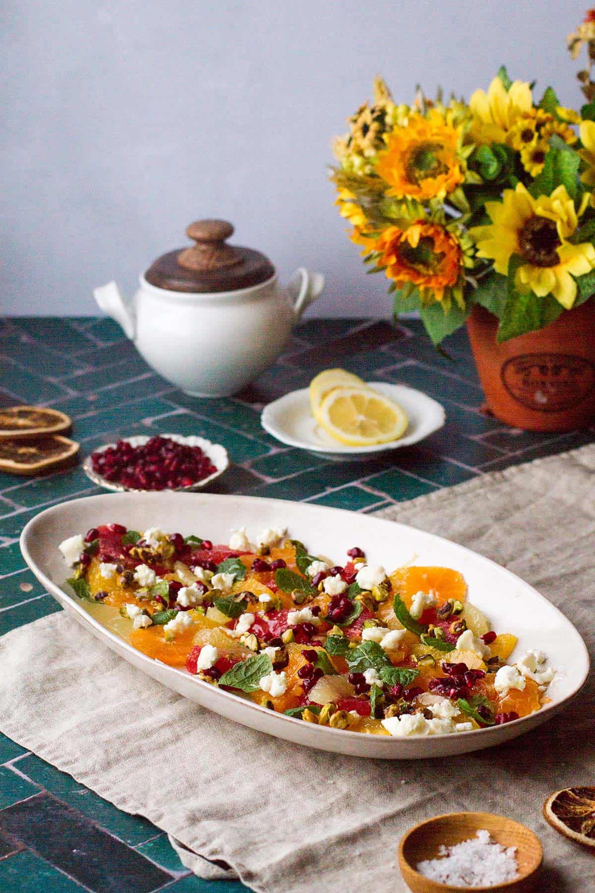 The citrus salad in one layer on a long plate, sunflowers in the background.