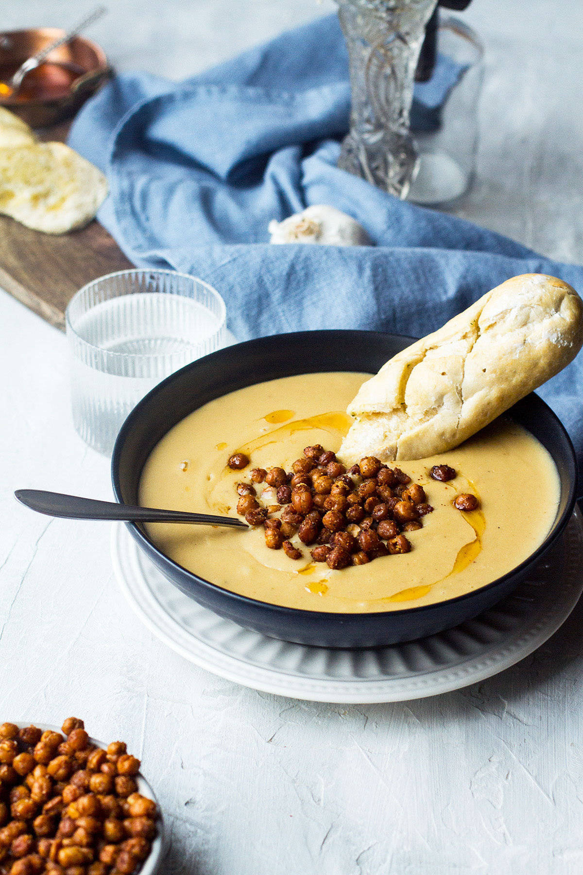 Chickpea soup in a dark bowl, with garlic bread and roasted chickpeas.