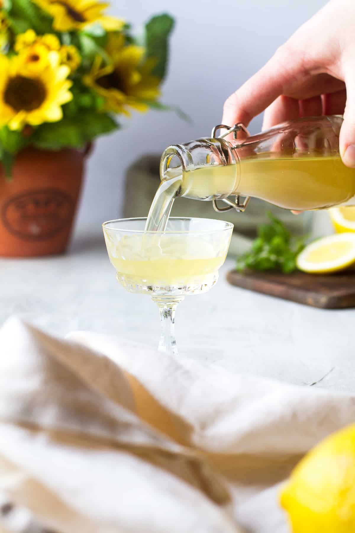 Pouring limoncello into a small, vintage glass.