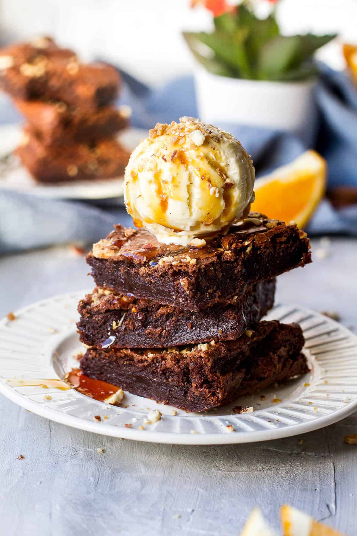 Stack of three brownies and a scoop of ice cream and caramel sauce.