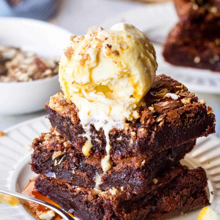 Stack of three slices of orange brownies with ice cream and almond crunch on top.