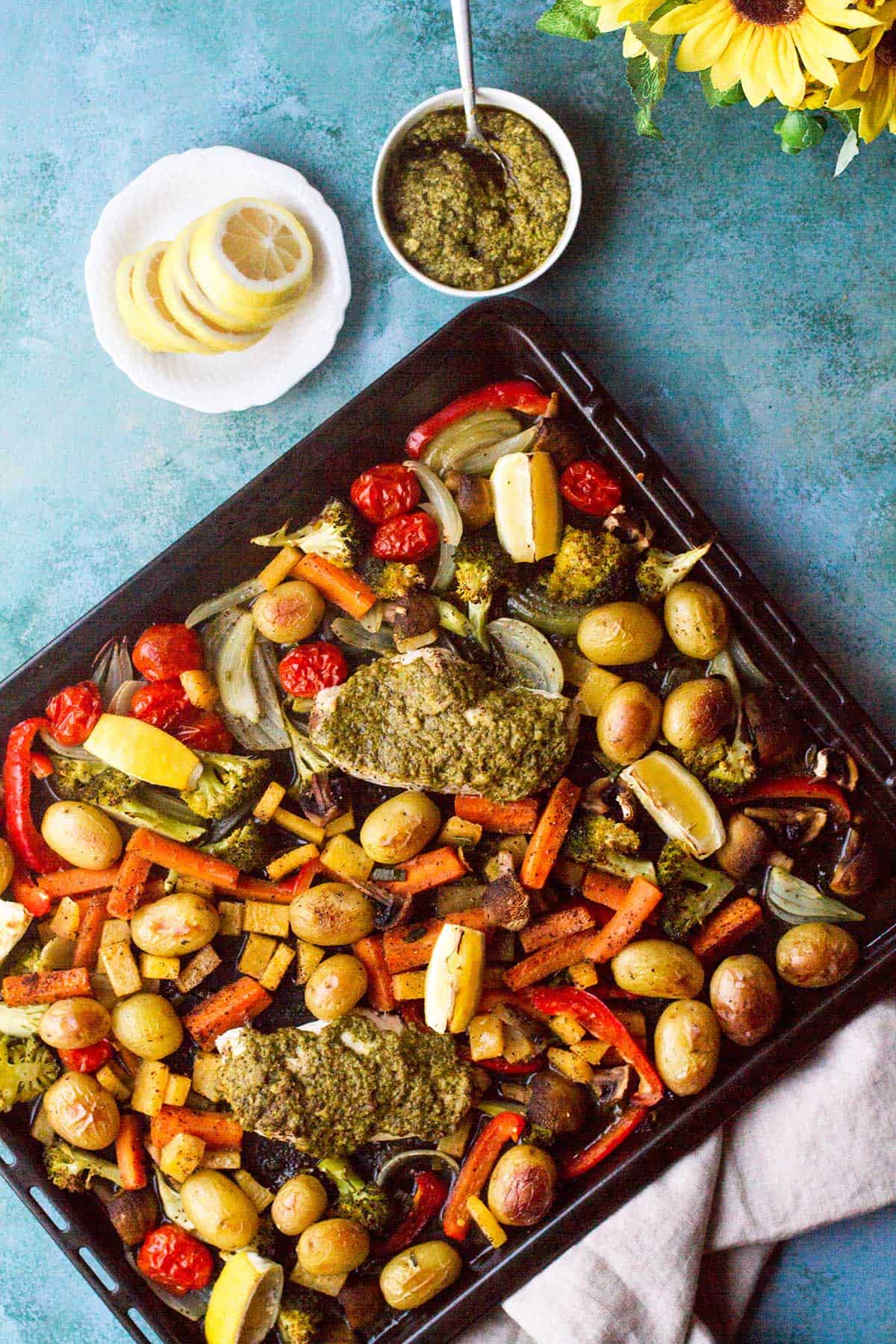 Baked pesto chicken and potatoes baking sheet, seen from above.