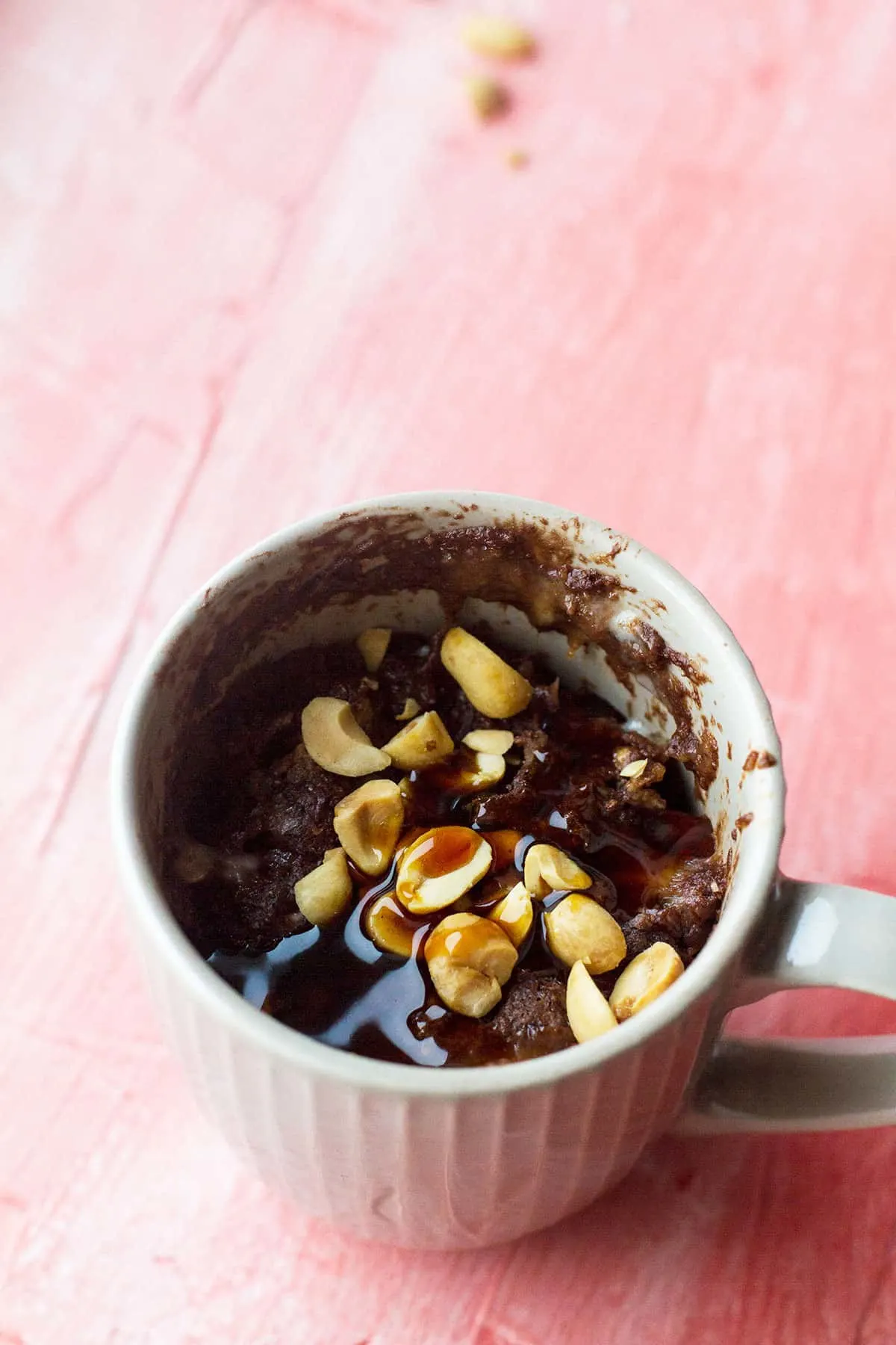Peanut caramel protein mug cake topped with peanuts and date syrup.
