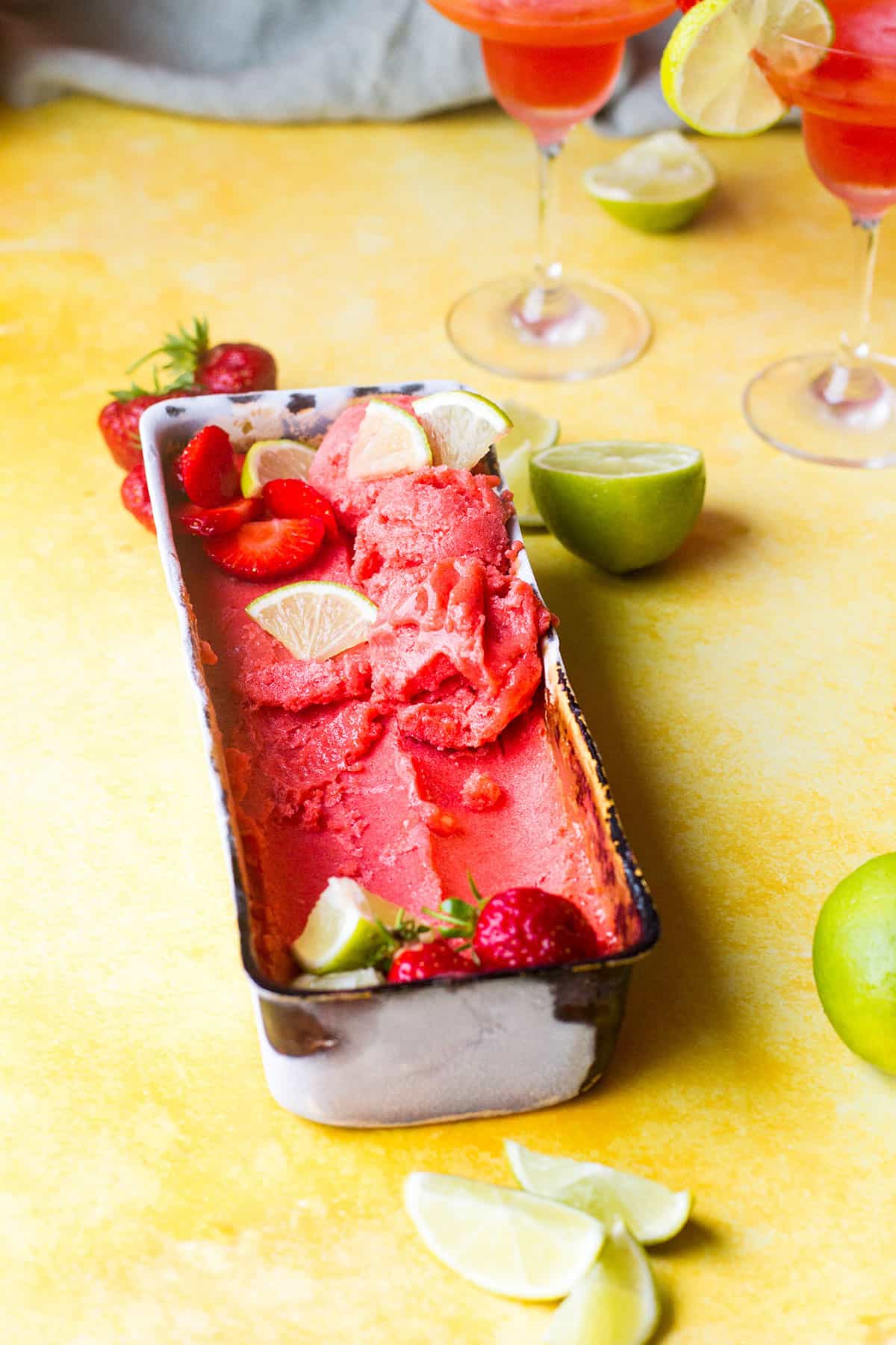 Bread pan with strawberry sorbet and lime slices.
