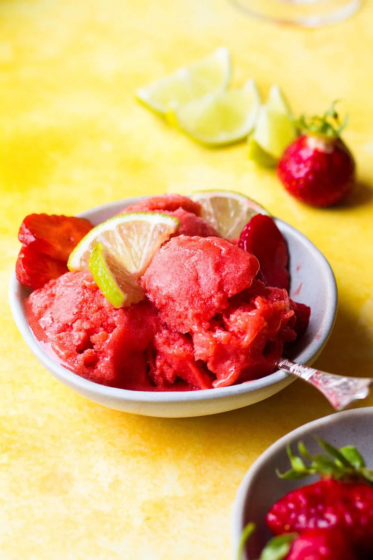 Strawberry sorbet and lime slices in a small bowl.