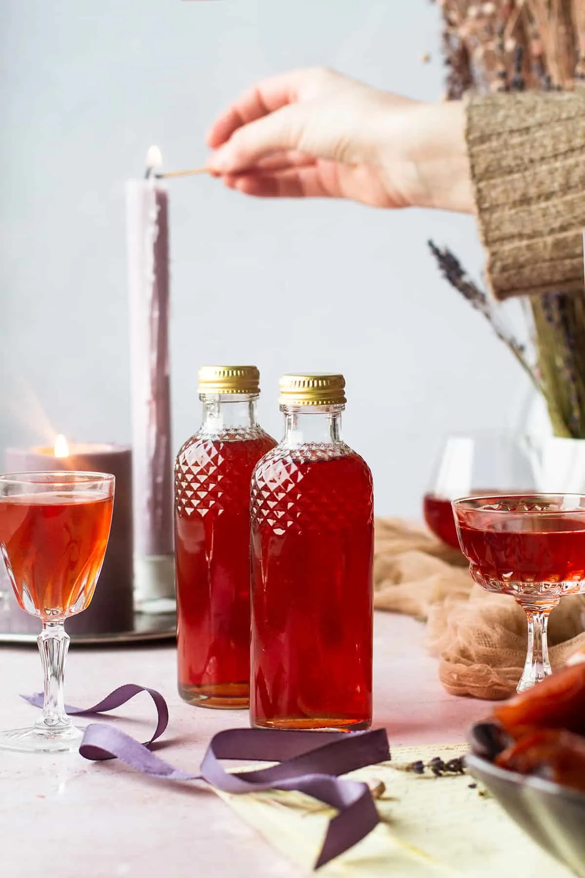 Two bottles of plum liqueur, hand lighting a candle in the background.
