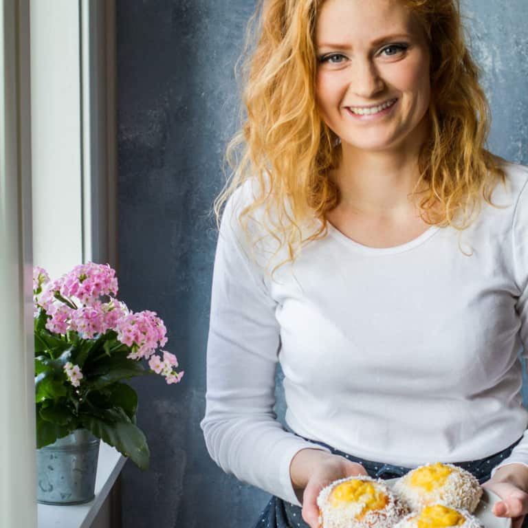 A girl with red curly hair holding a plate of vanilla custard buns.