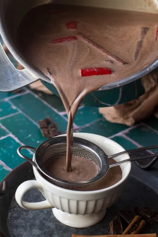 Pouring hot chocolate in a small cup.