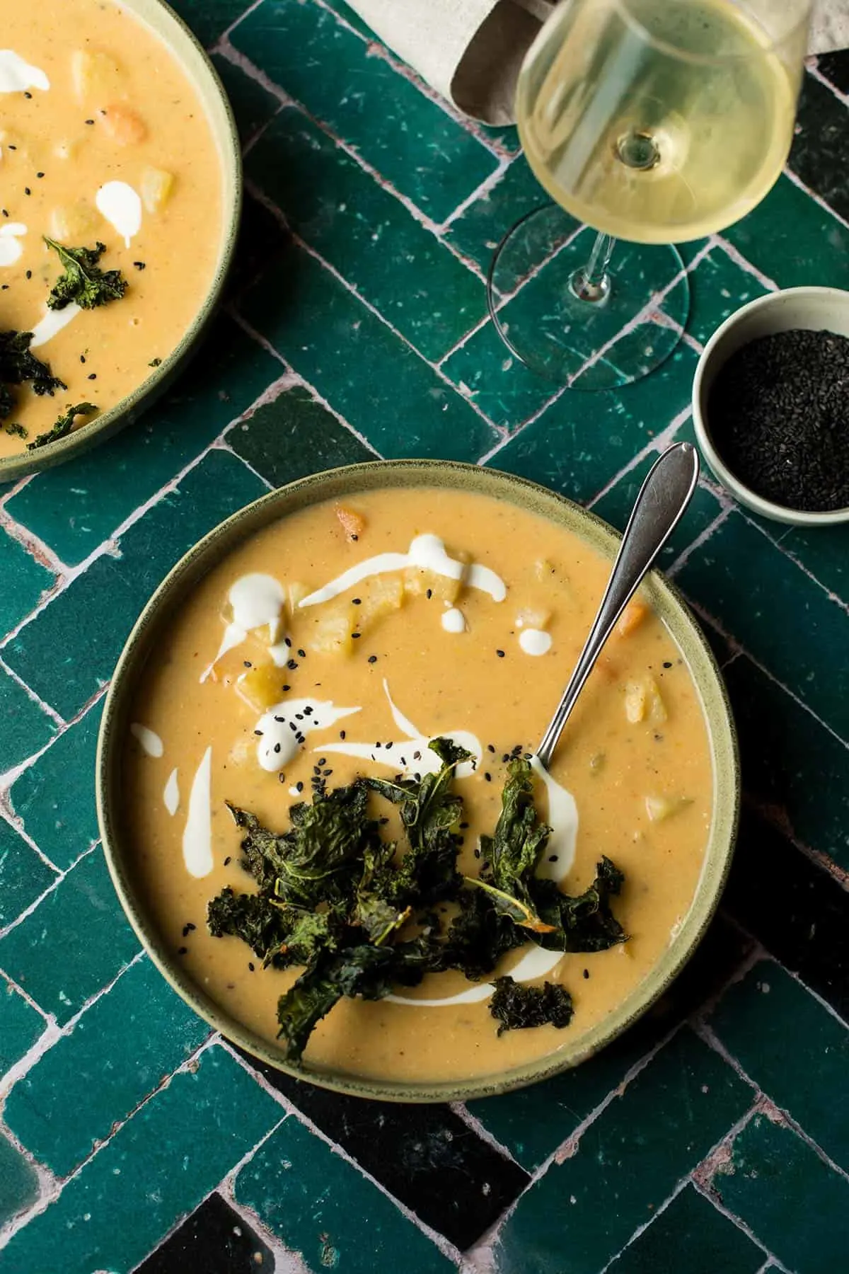 Potato and carrot soup topped with kale chips, seen from above.