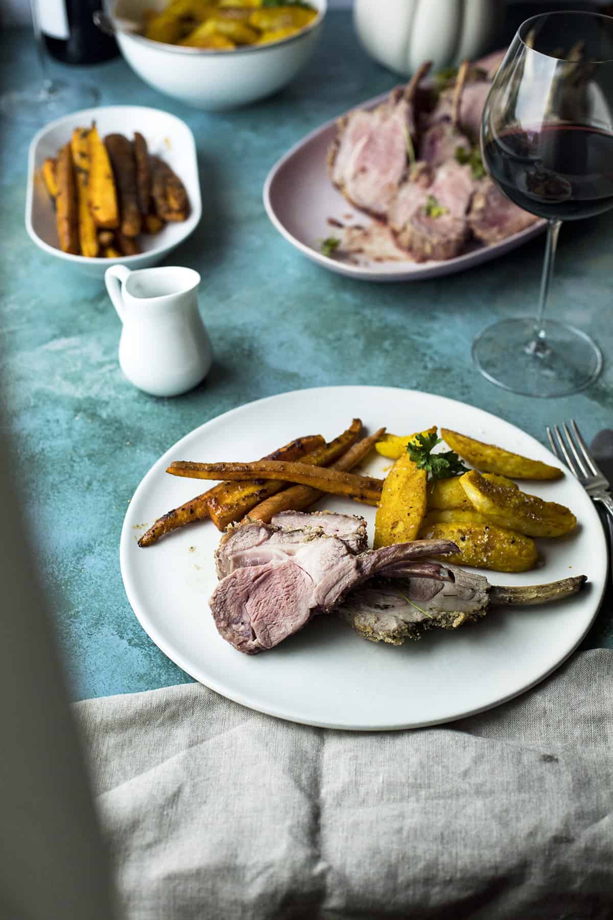 Close-up of a slice of lamb and roasted carrots and turmeric potatoes.