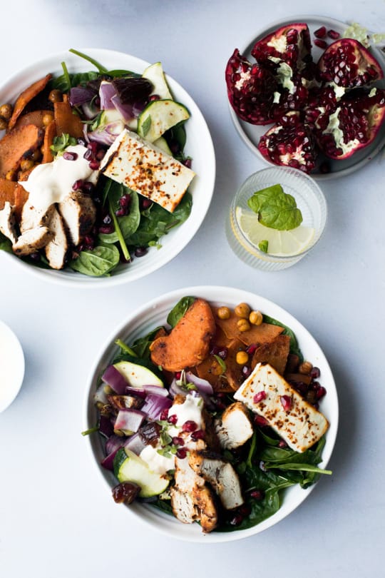 Close-up of two white bowls with salad with roasted vegetables, chicken and feta cheese.