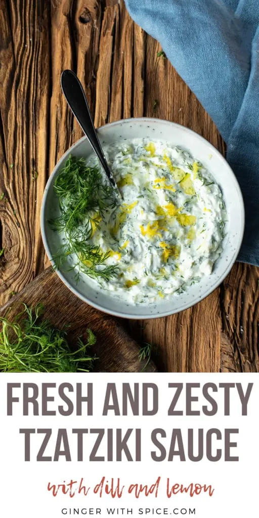 Close-up of tzatziki sauce with fresh dill and lemon zest on top. Pinterest pin.