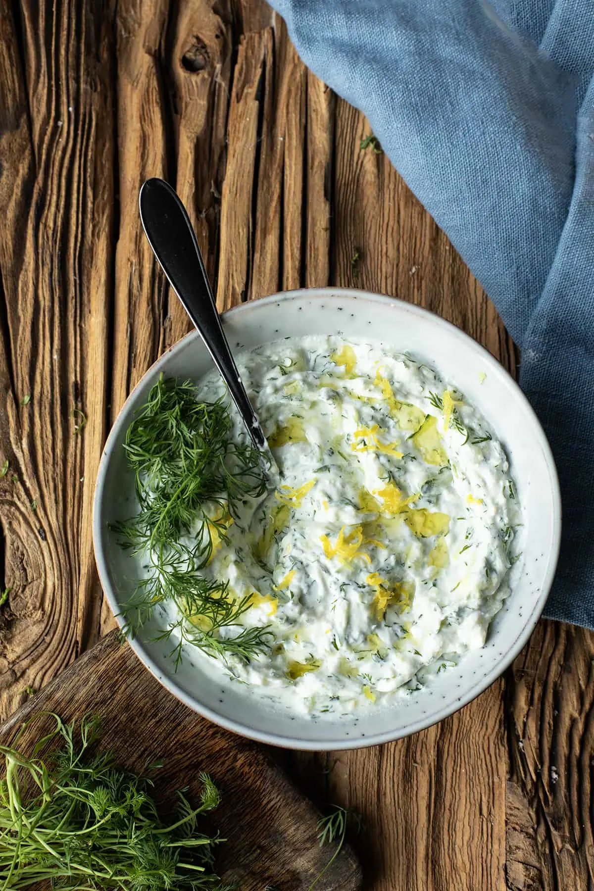 Close-up of tzatziki sauce with fresh dill and lemon zest on top.