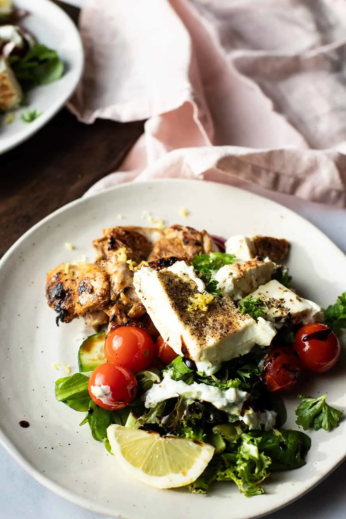 Baked feta cheese over a bed of salad and grilled chicken.