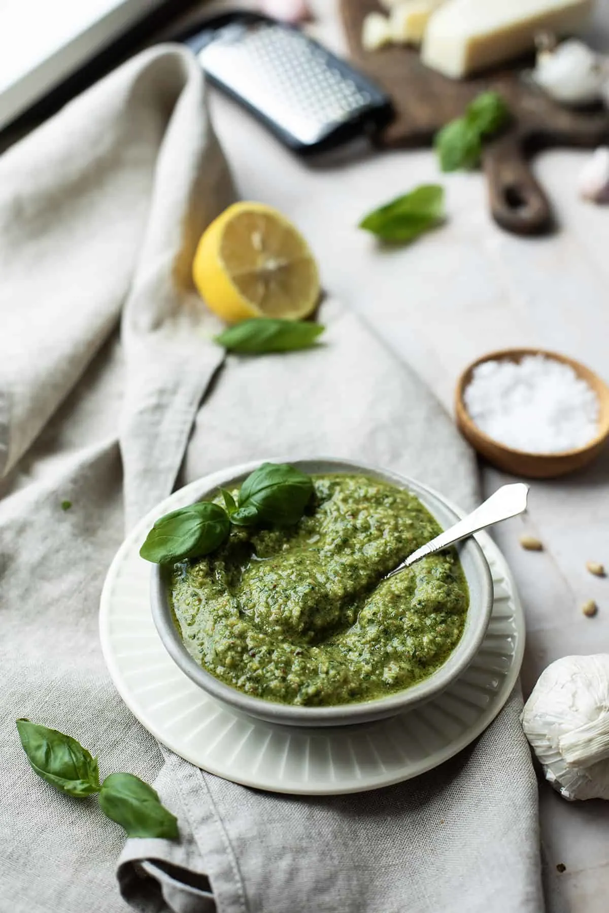 A white bowl with pesto alla Genovese, garnished with fresh basil.