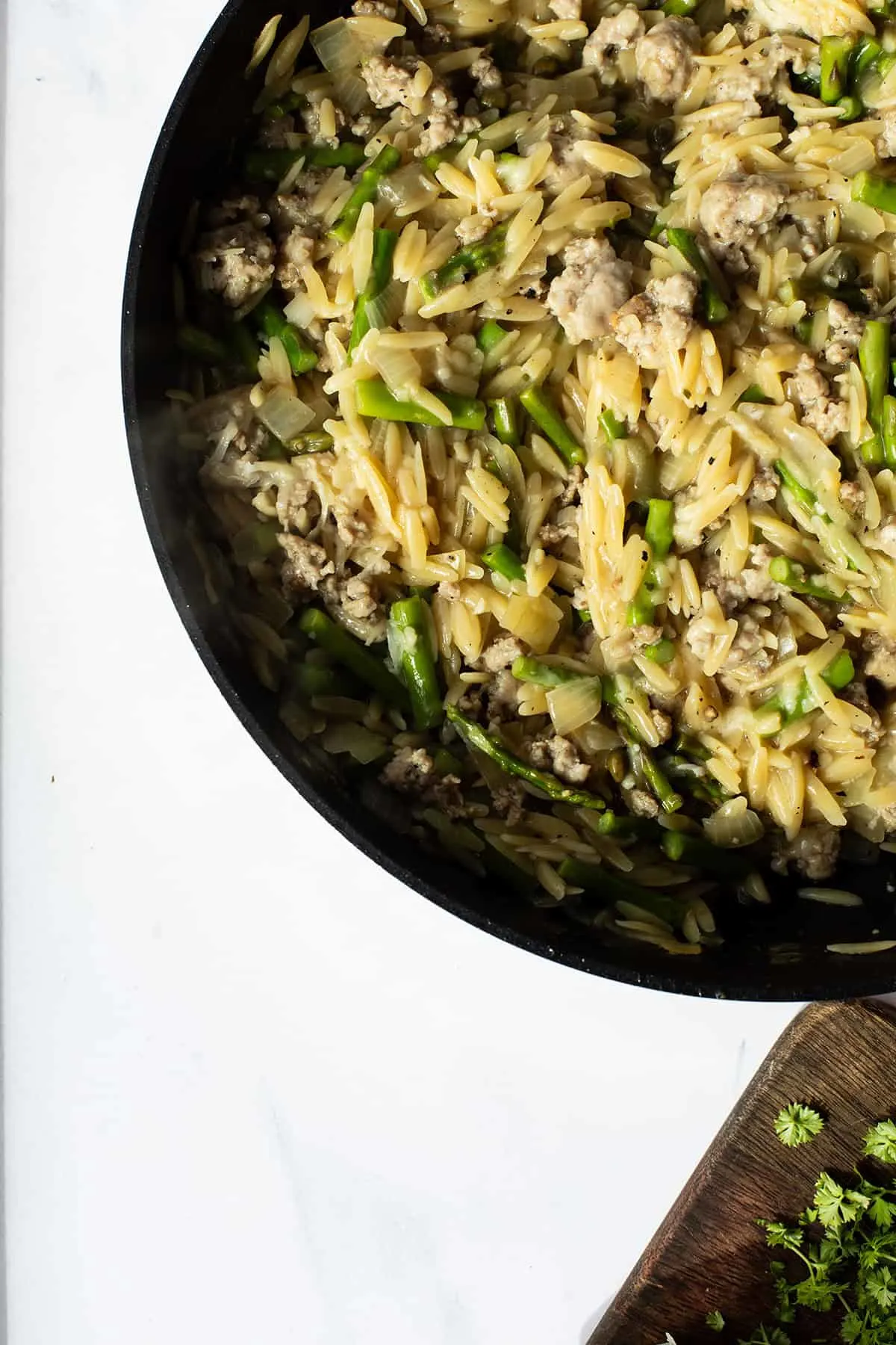 Close-up of a skillet with lemon parmesan sausage orzo.