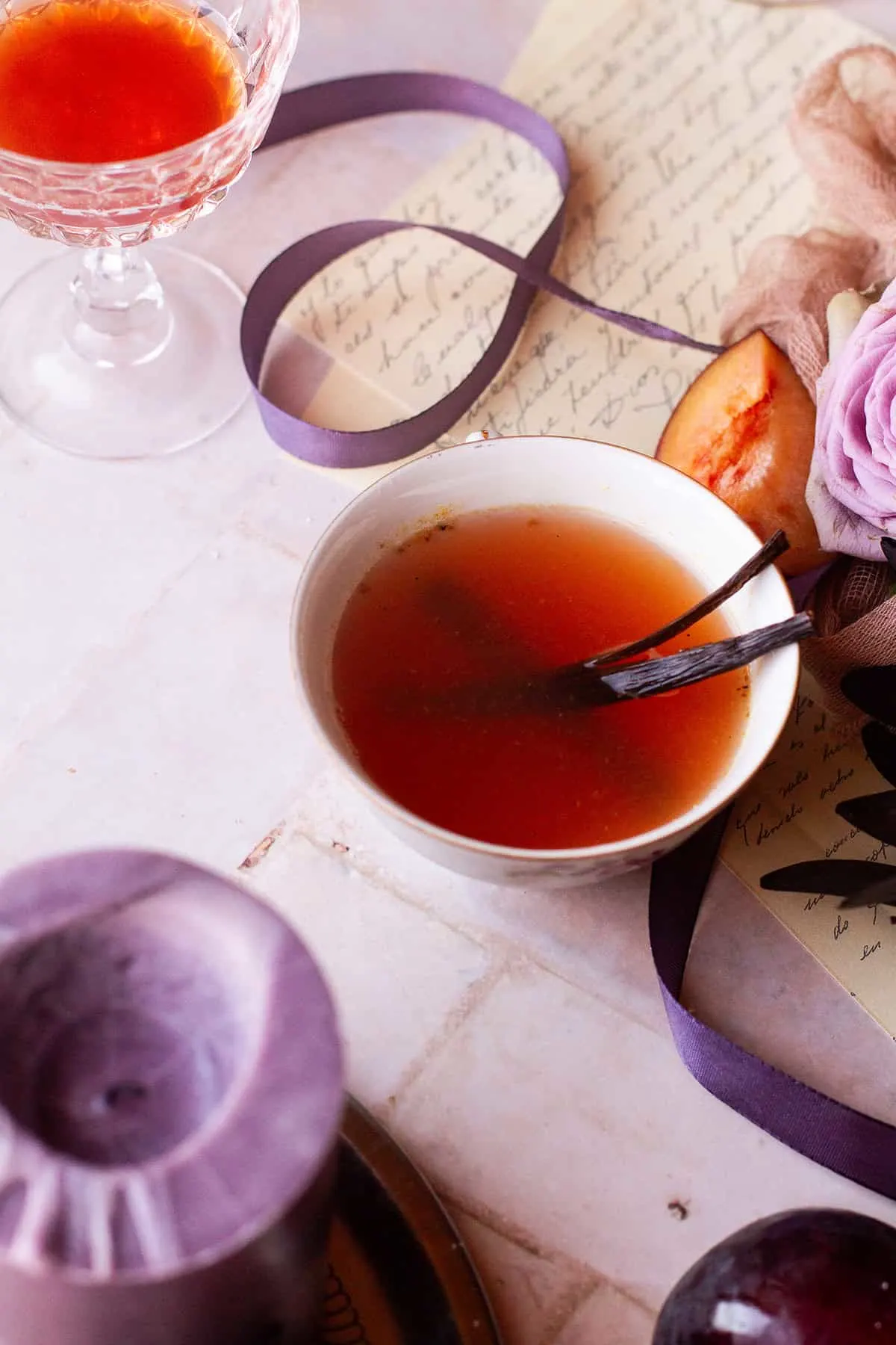 Small cup with spiced plum cider garnished with vanilla beans.