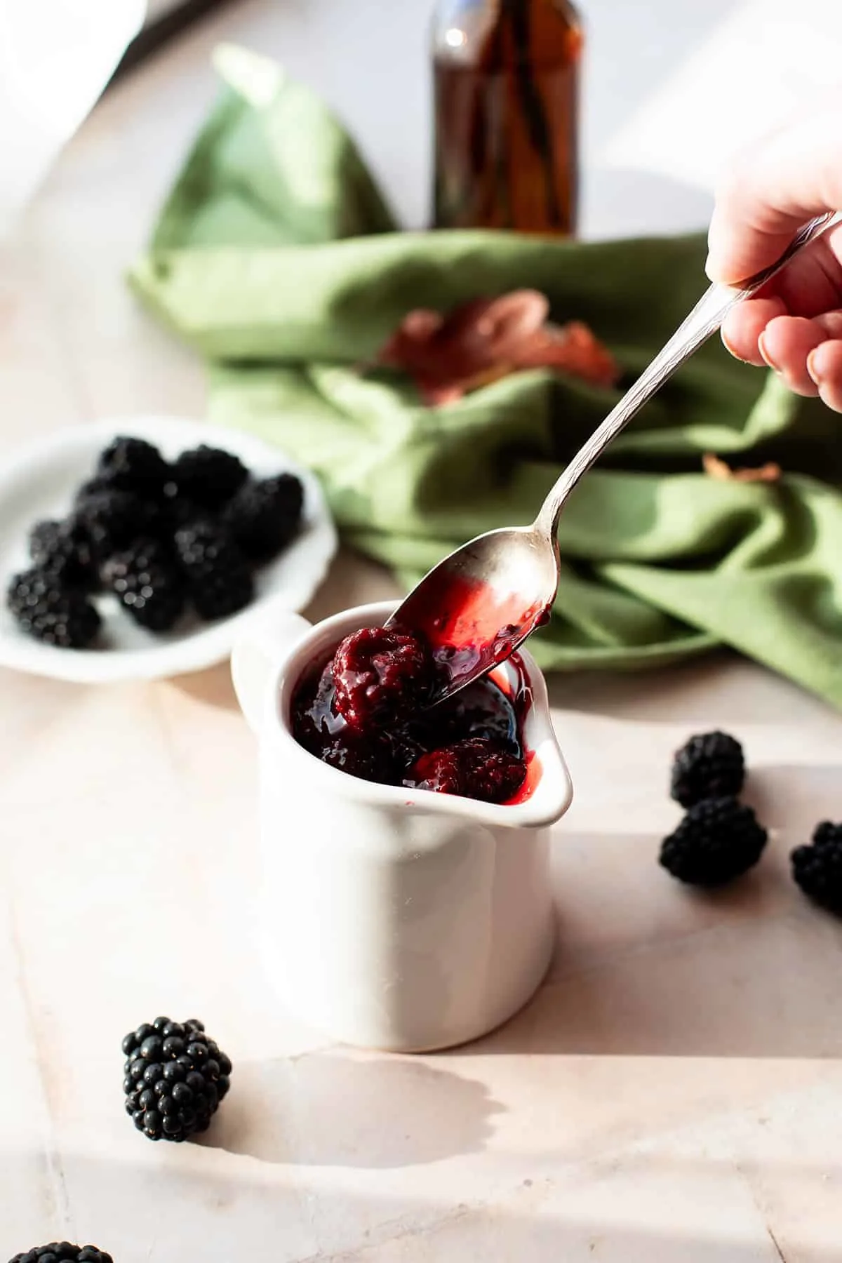 Taking a spoon of blackberry sauce from the white jug.
