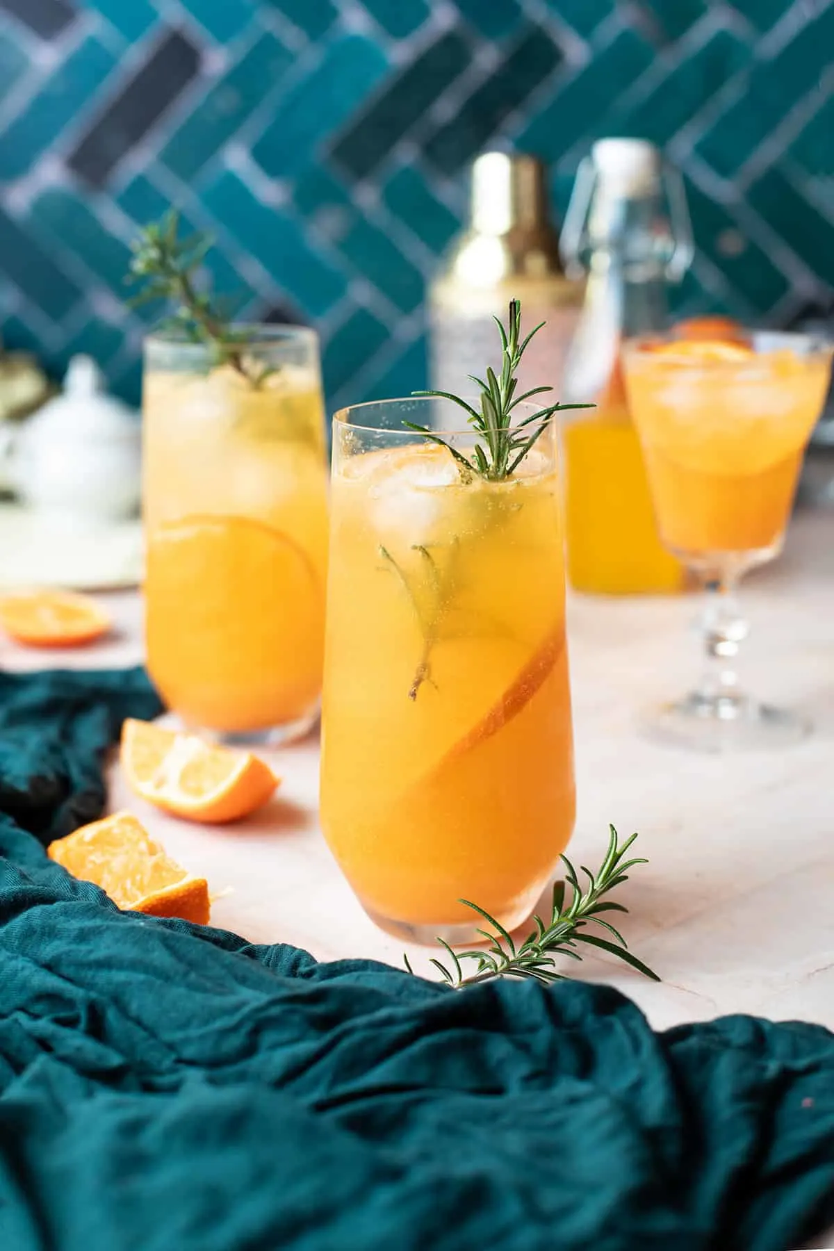 Mandarin cocktail in stemless champagne flutes, garnished with fresh rosemary.
