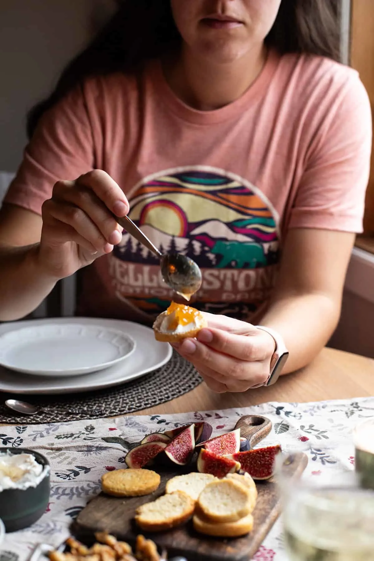 Hand dolloping fig jam on crostini.