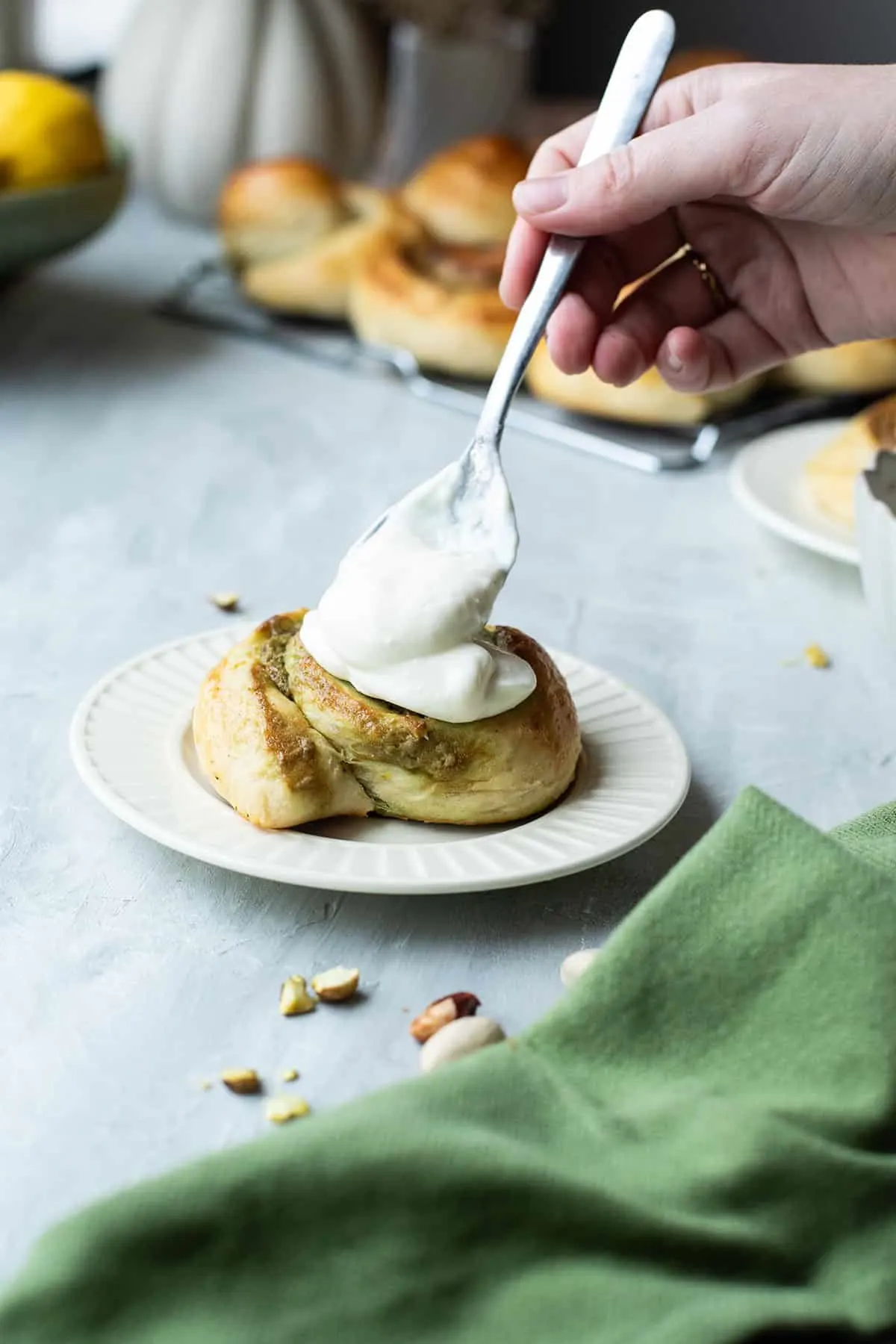 Drizzling cream cheese frosting on top of one bun.