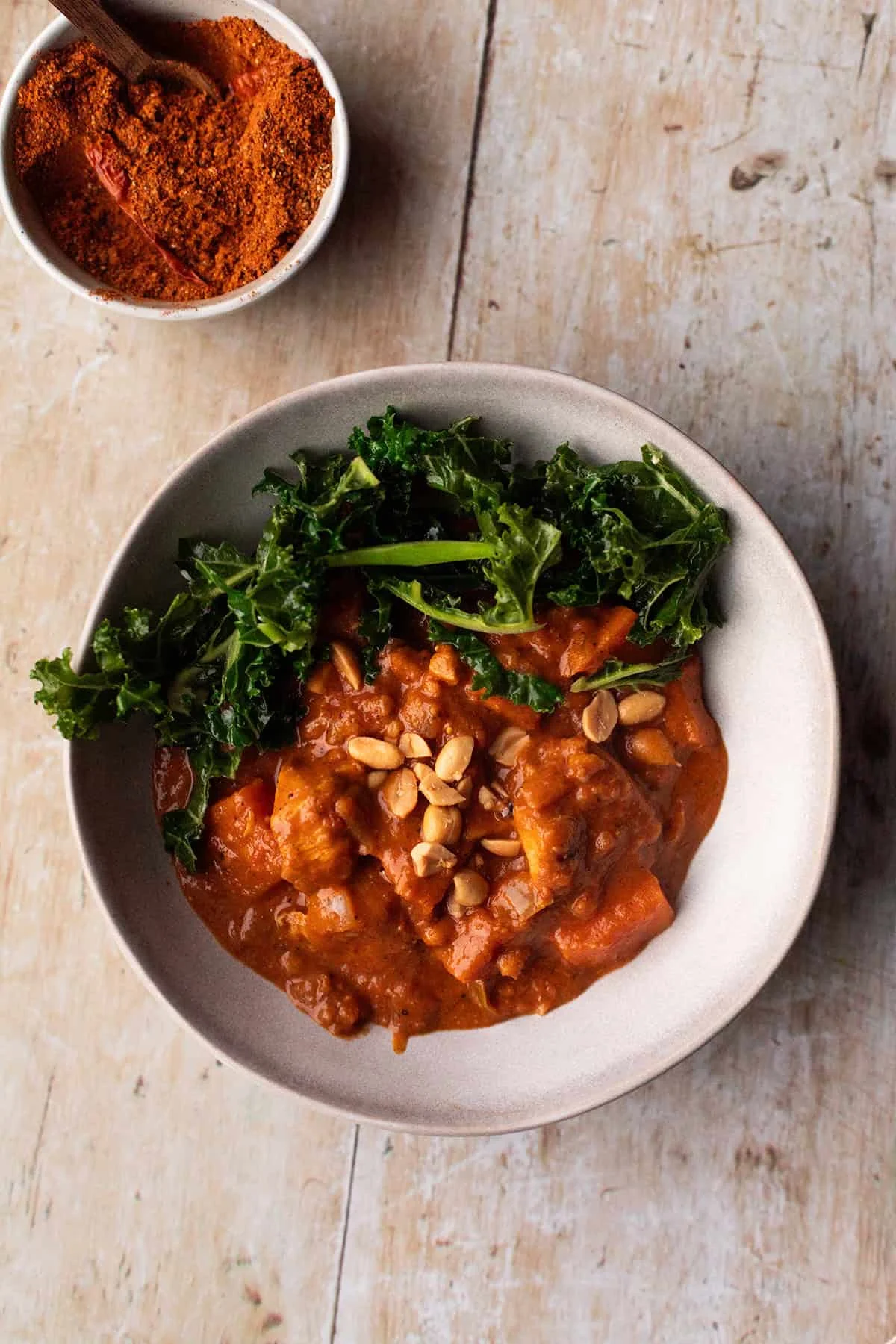 Serving bowl with chicken peanut stew and garlic kale.