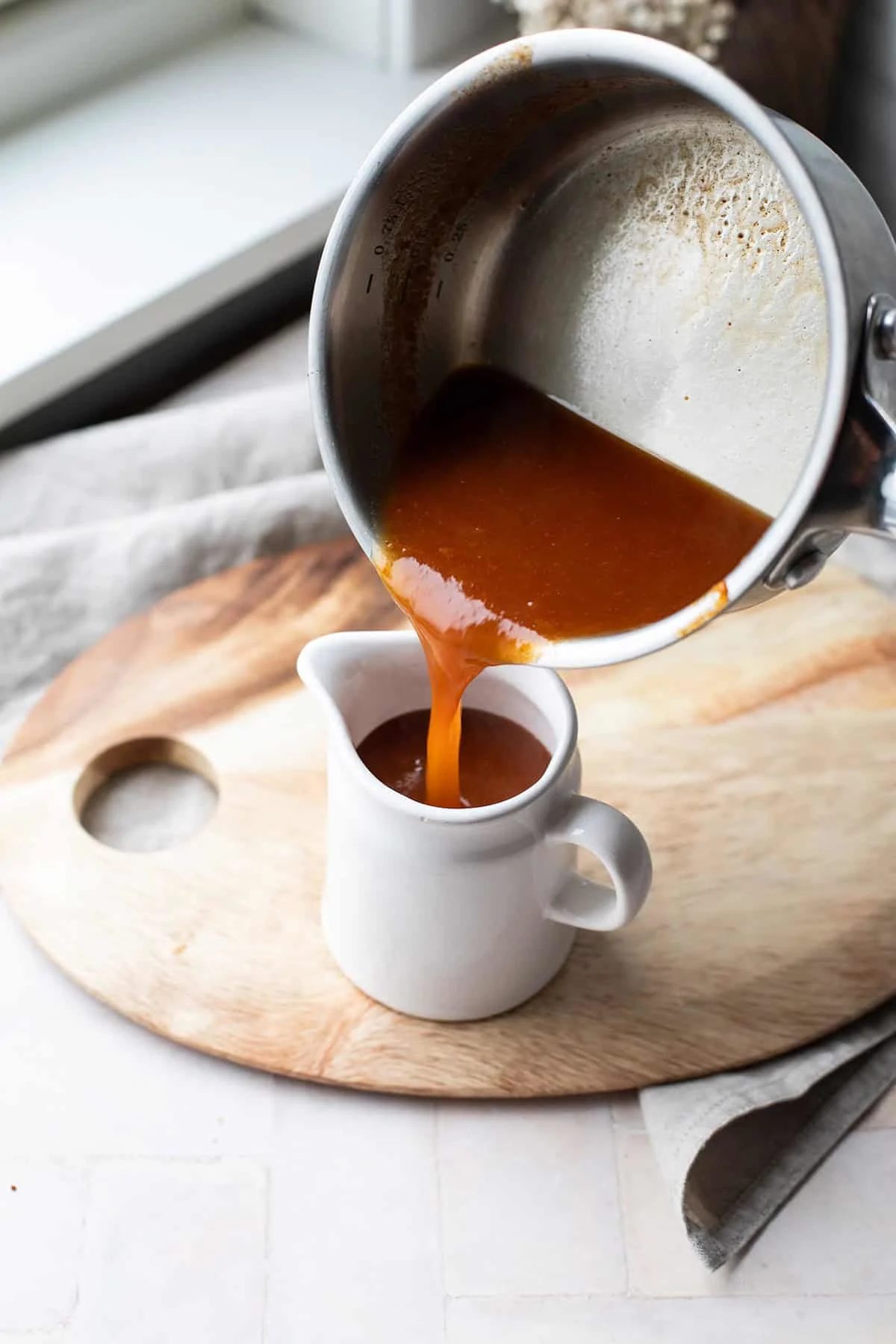 Pouring apricot sauce into a small serving jar.