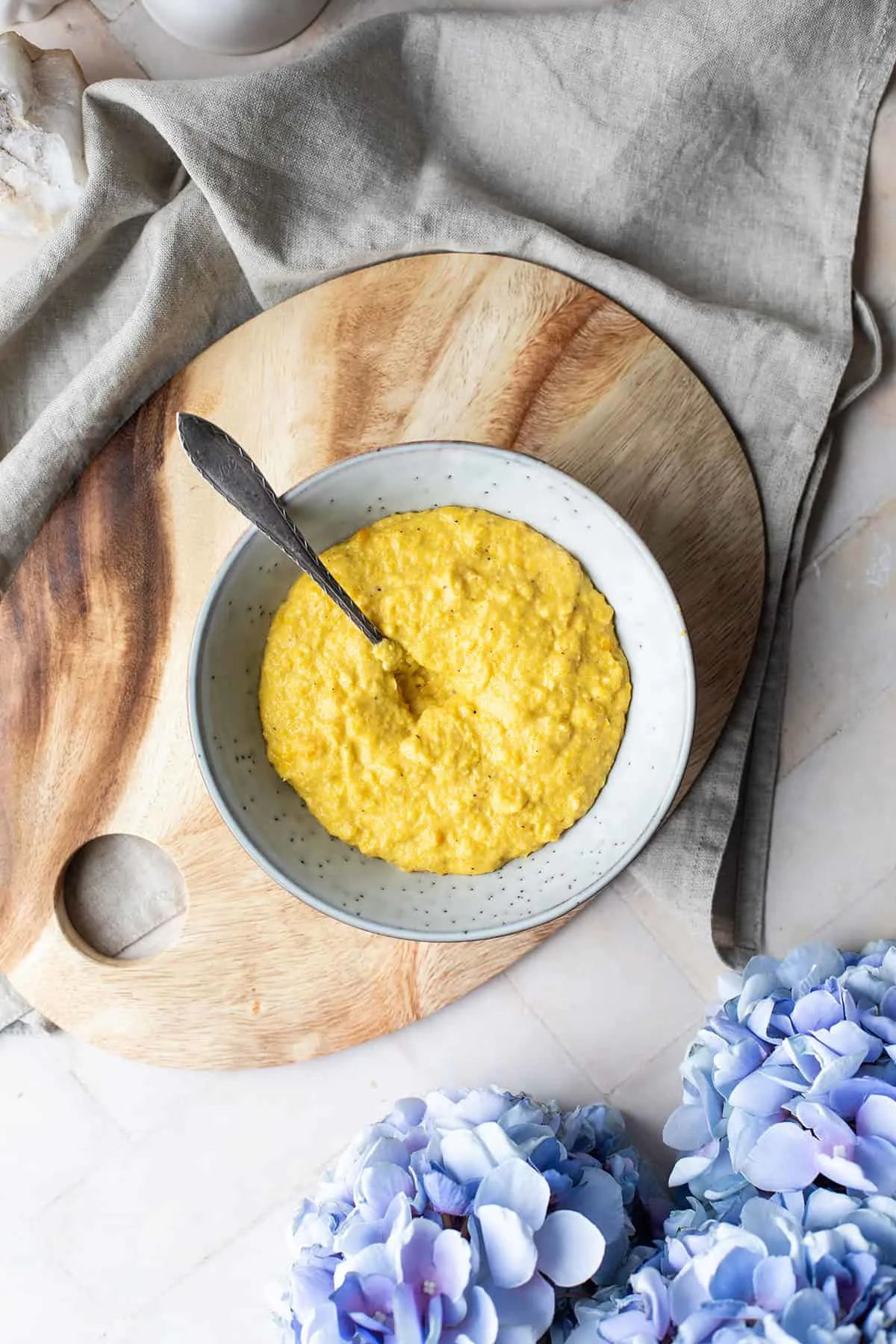 Creamed corn in a bowl on a cutting board. Seen from above.
