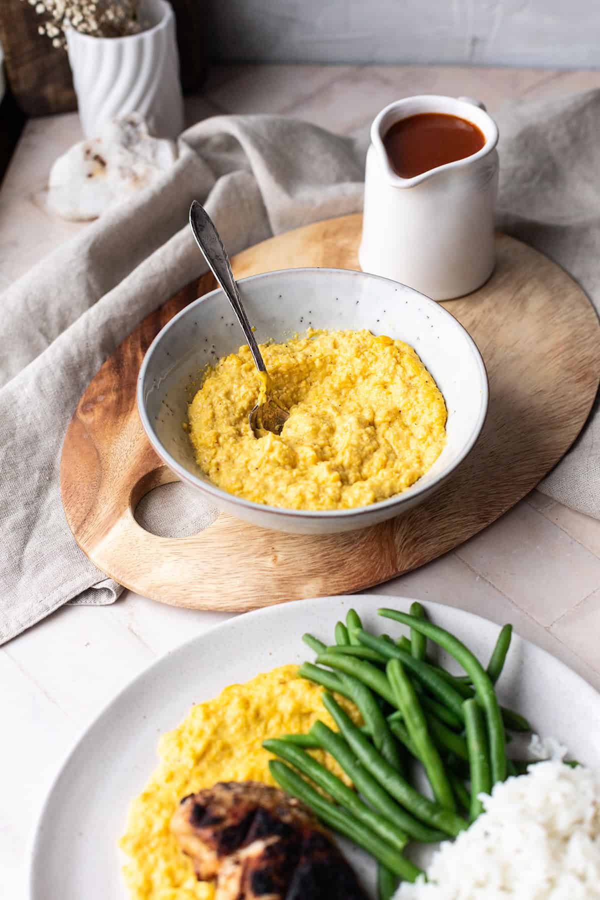 Creamed corn and apricot BBQ sauce on a cutting board, finished dish in the foreground.
